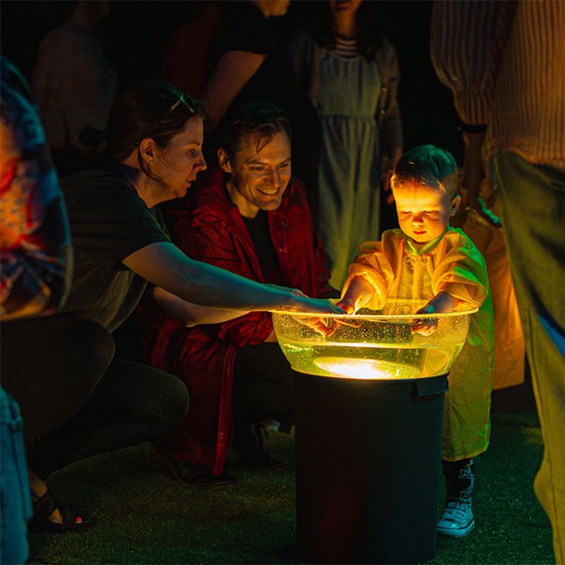 Child and parents interacting with illuminated bowl of water