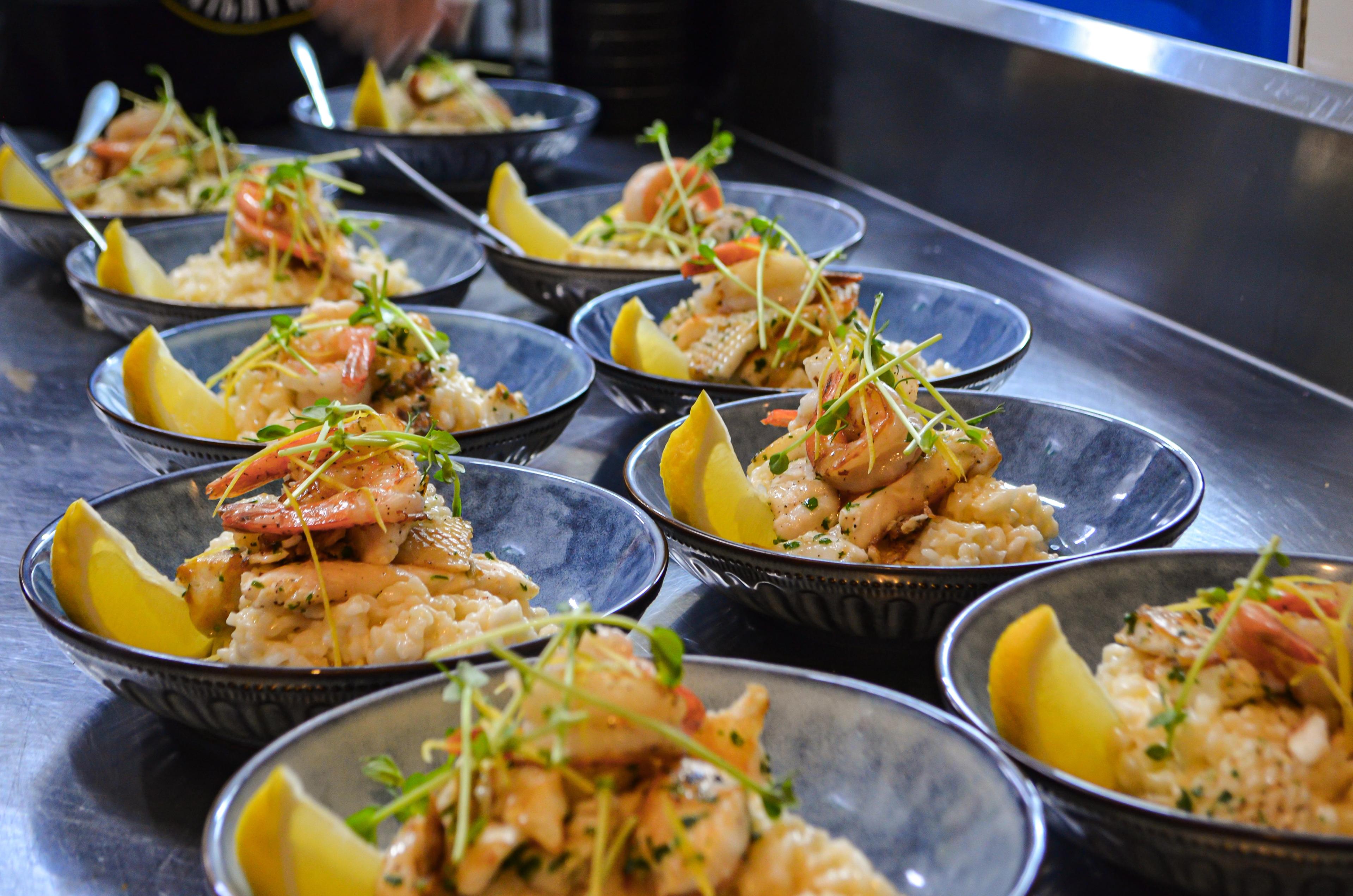 Bowl of risotto are topped with prawns and lemon wedges