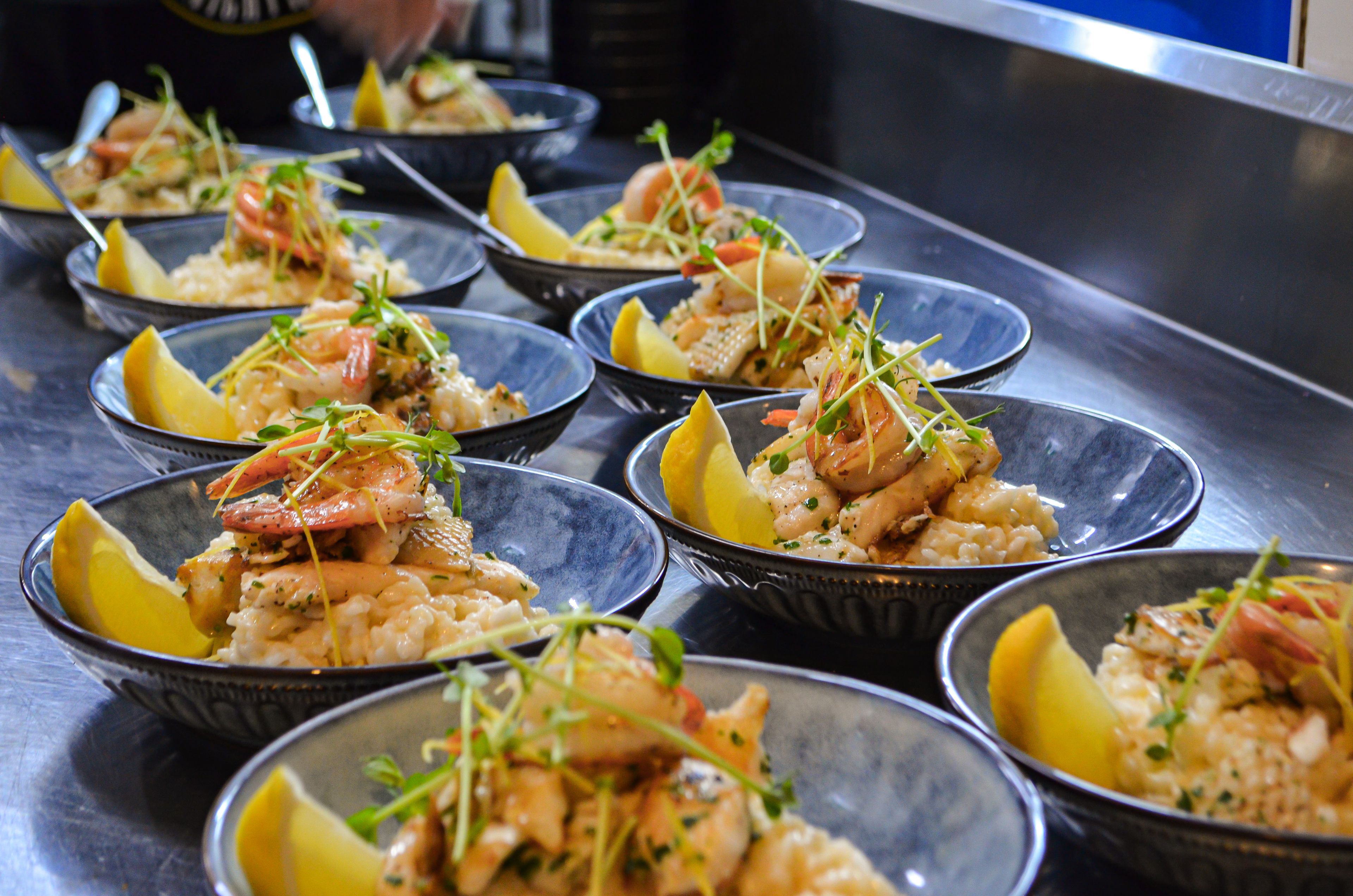 Bowl of risotto are topped with prawns and lemon wedges