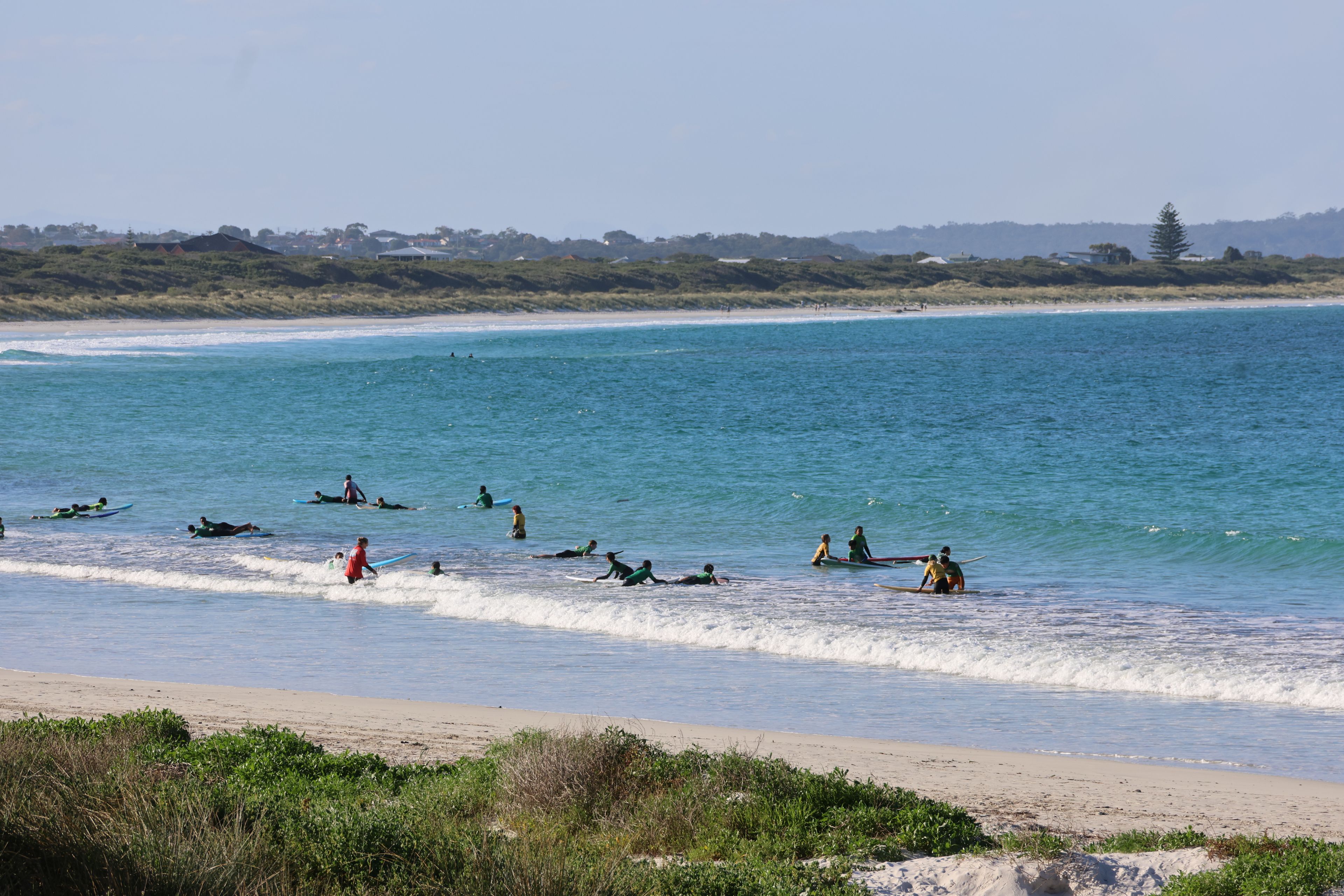 A surf school out in the water at Binalup on a clear day