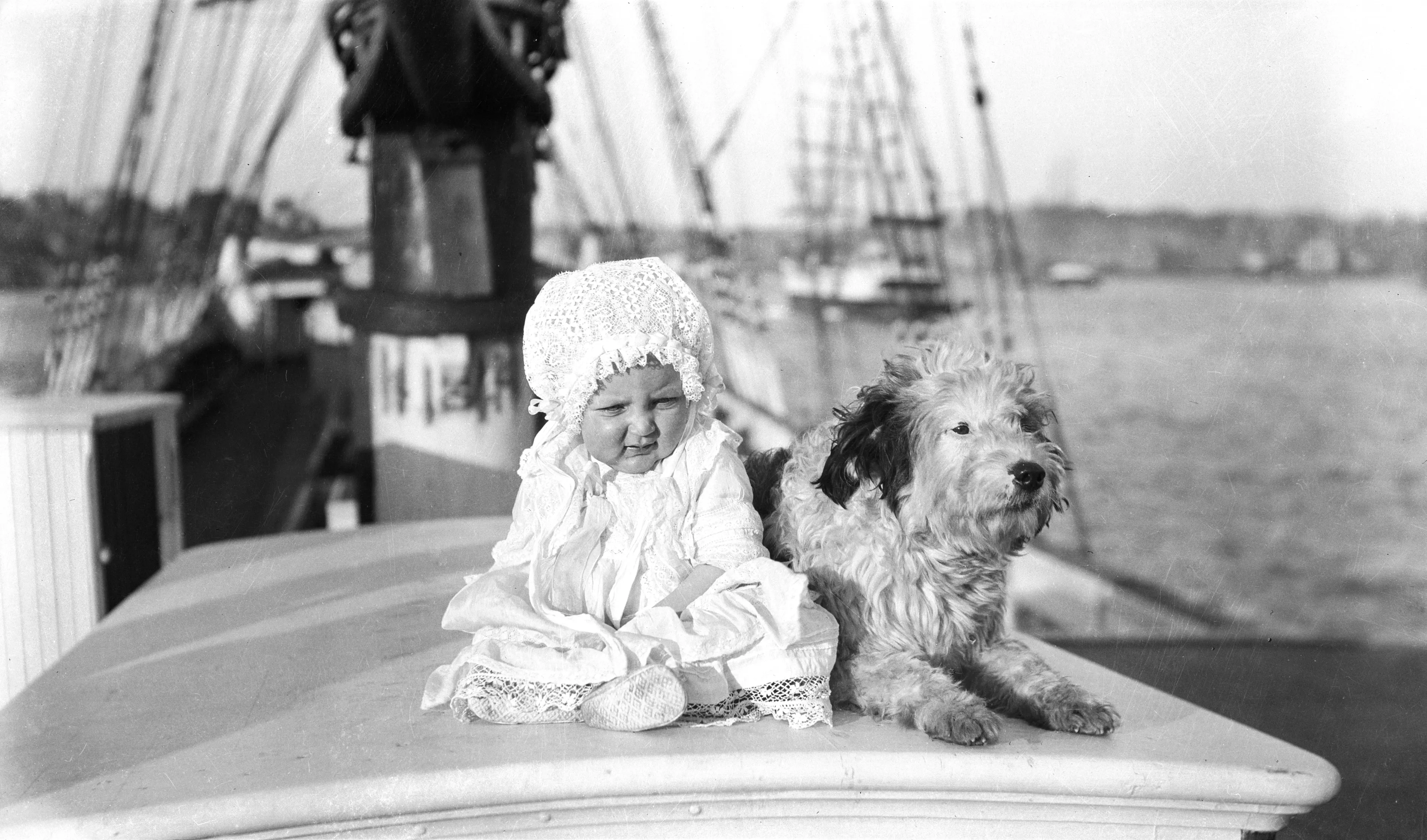 Historic image of a baby and dog sitting on a ship