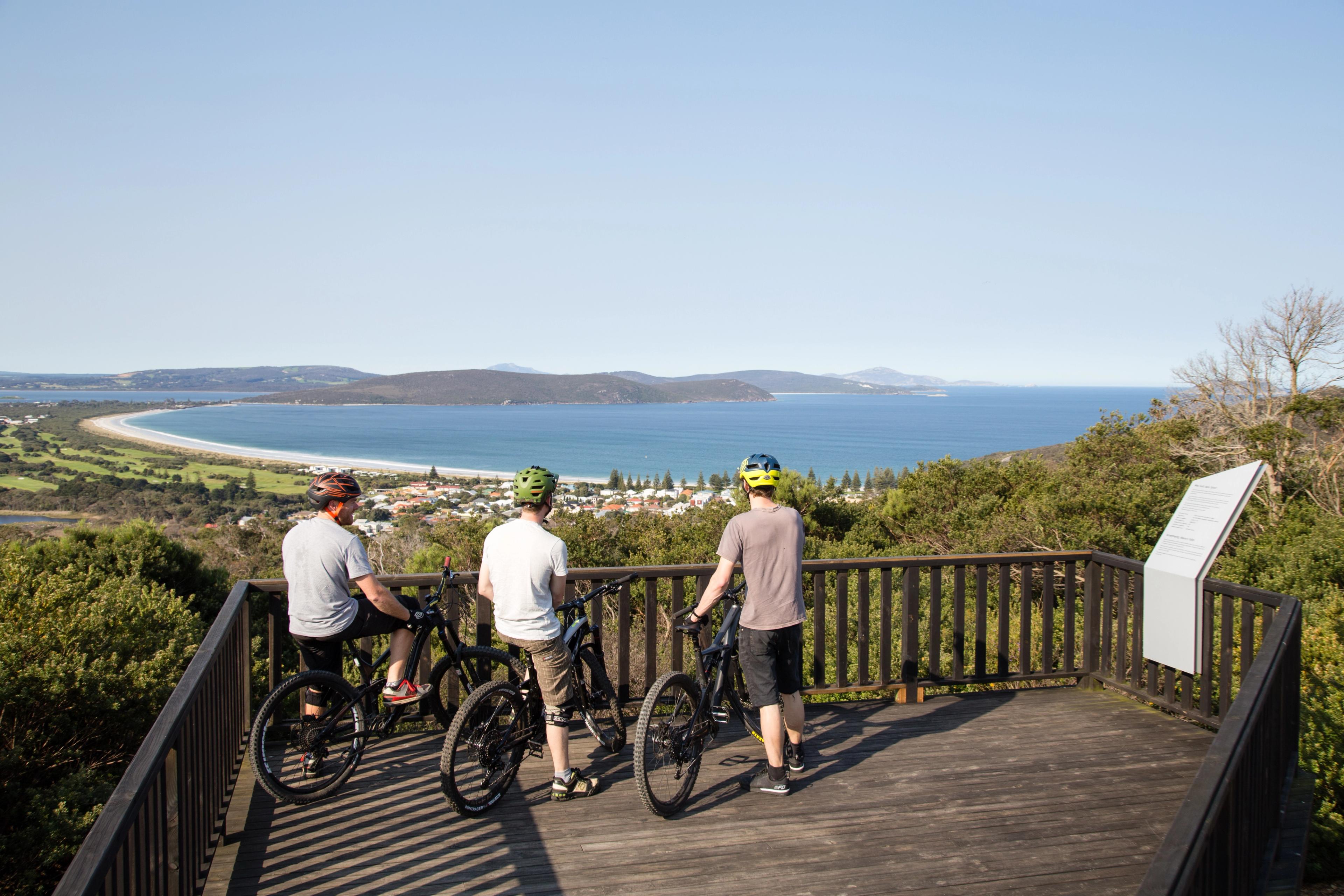 Three men on bikes at the top of a lookout enjoying the view