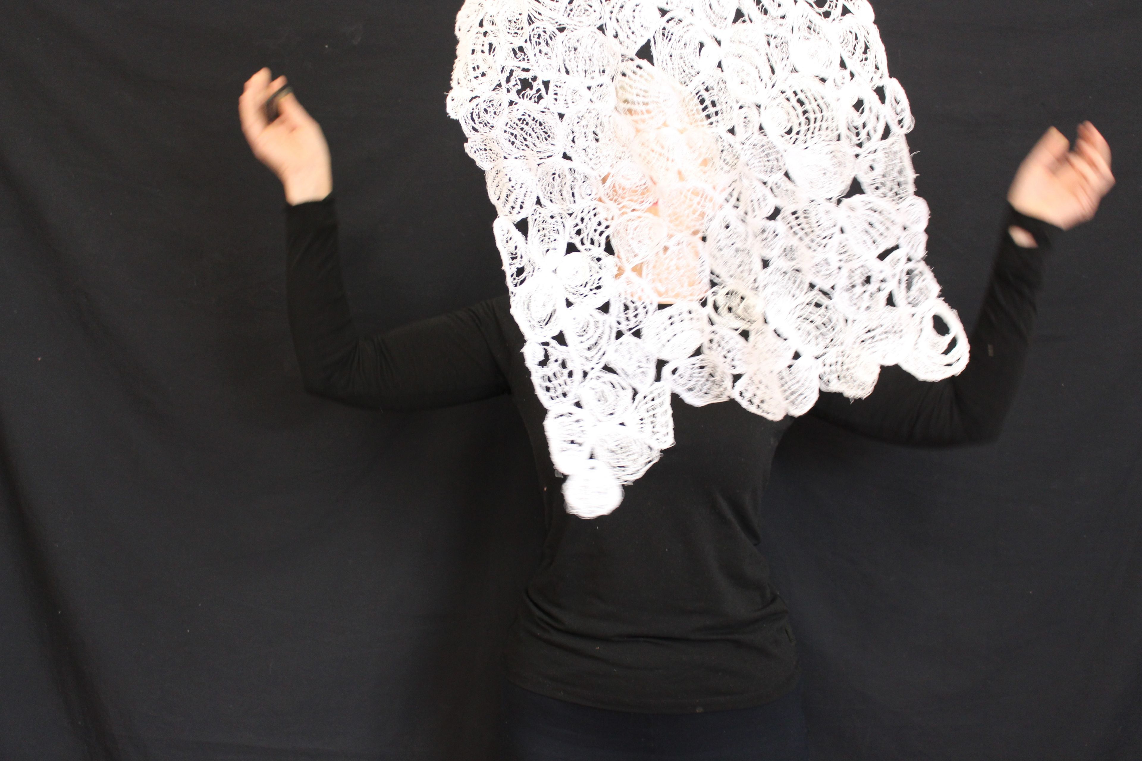 Embroidered white lace gets thrown into the air before a black backdrop