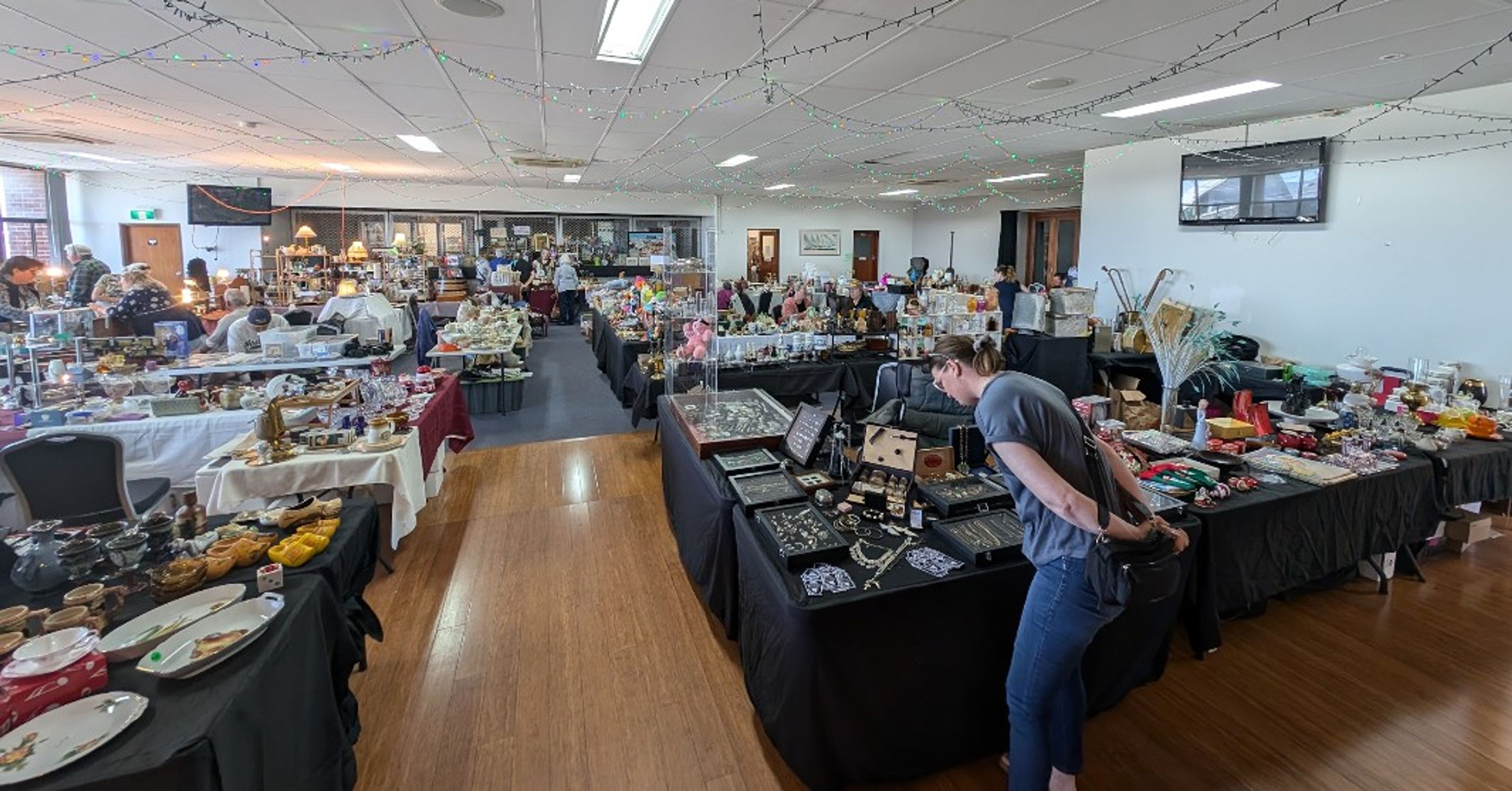 Room set up with tables of antiques and person leaning over to look closely at an item