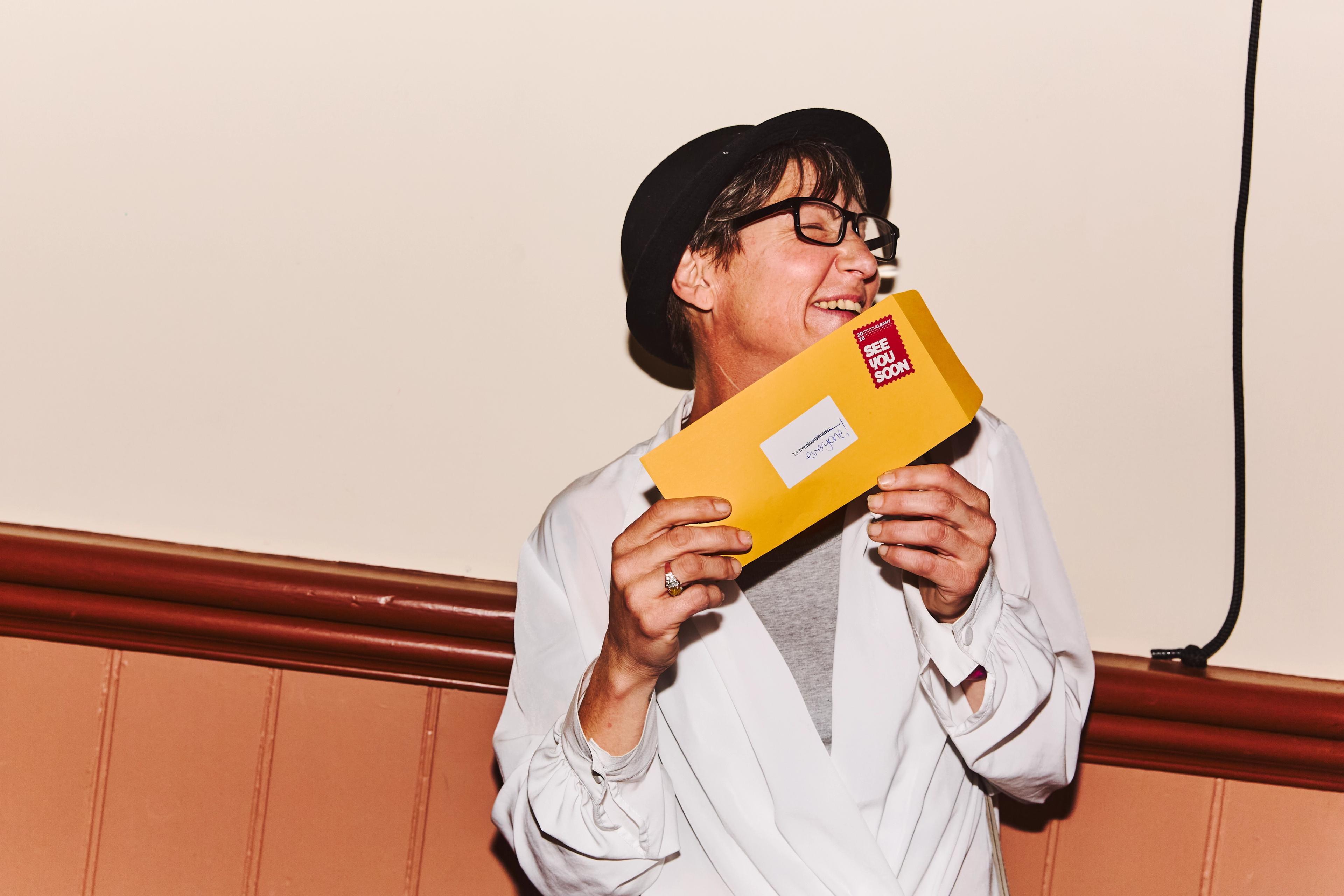 A photo of a lady holding an envelope wearing a black hat