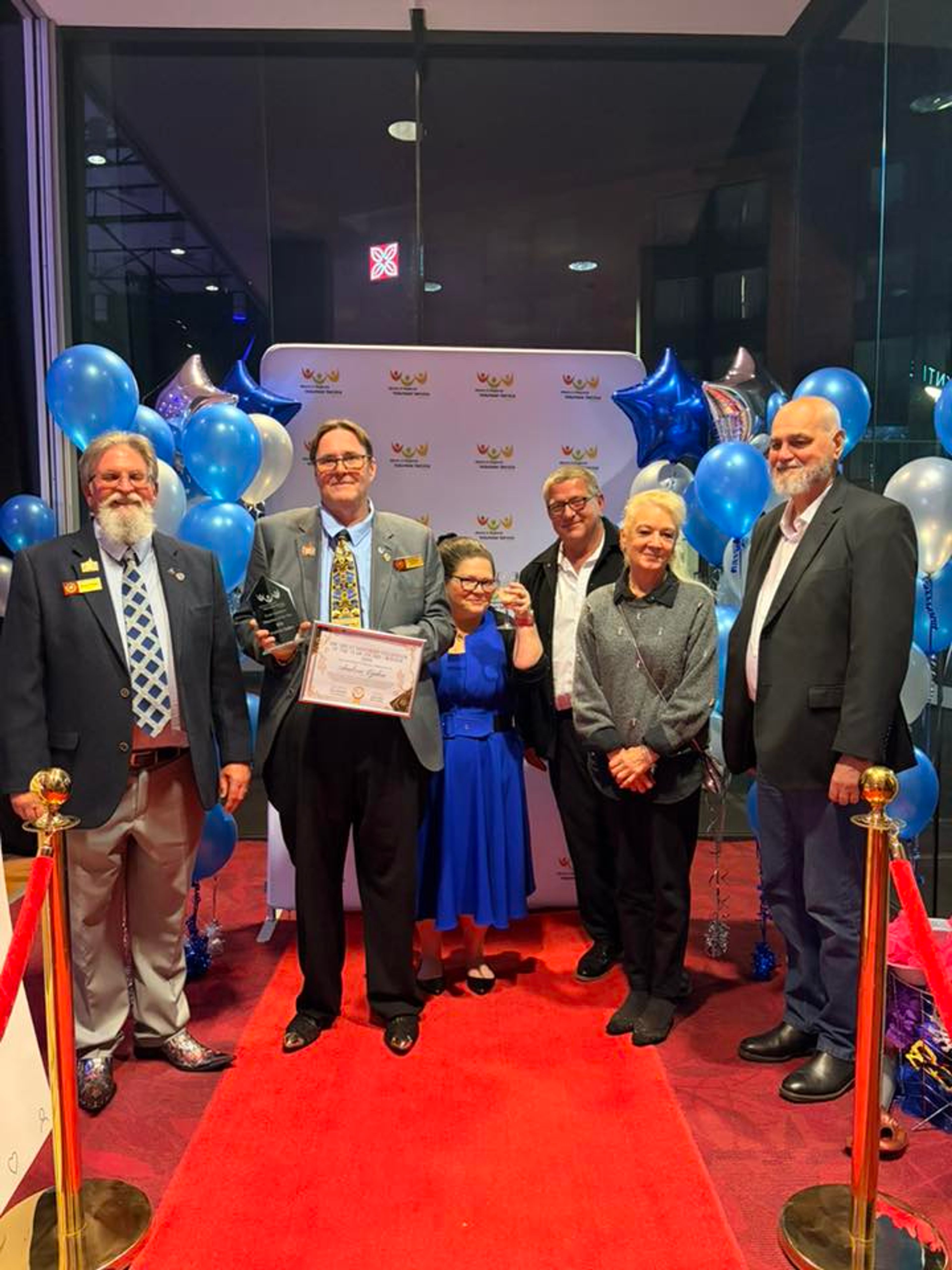 Andrew Eyden holding award at end of red carpet with AHS volunteers