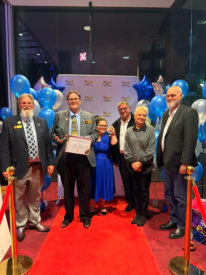 Andrew Eyden holding award at end of red carpet with AHS volunteers