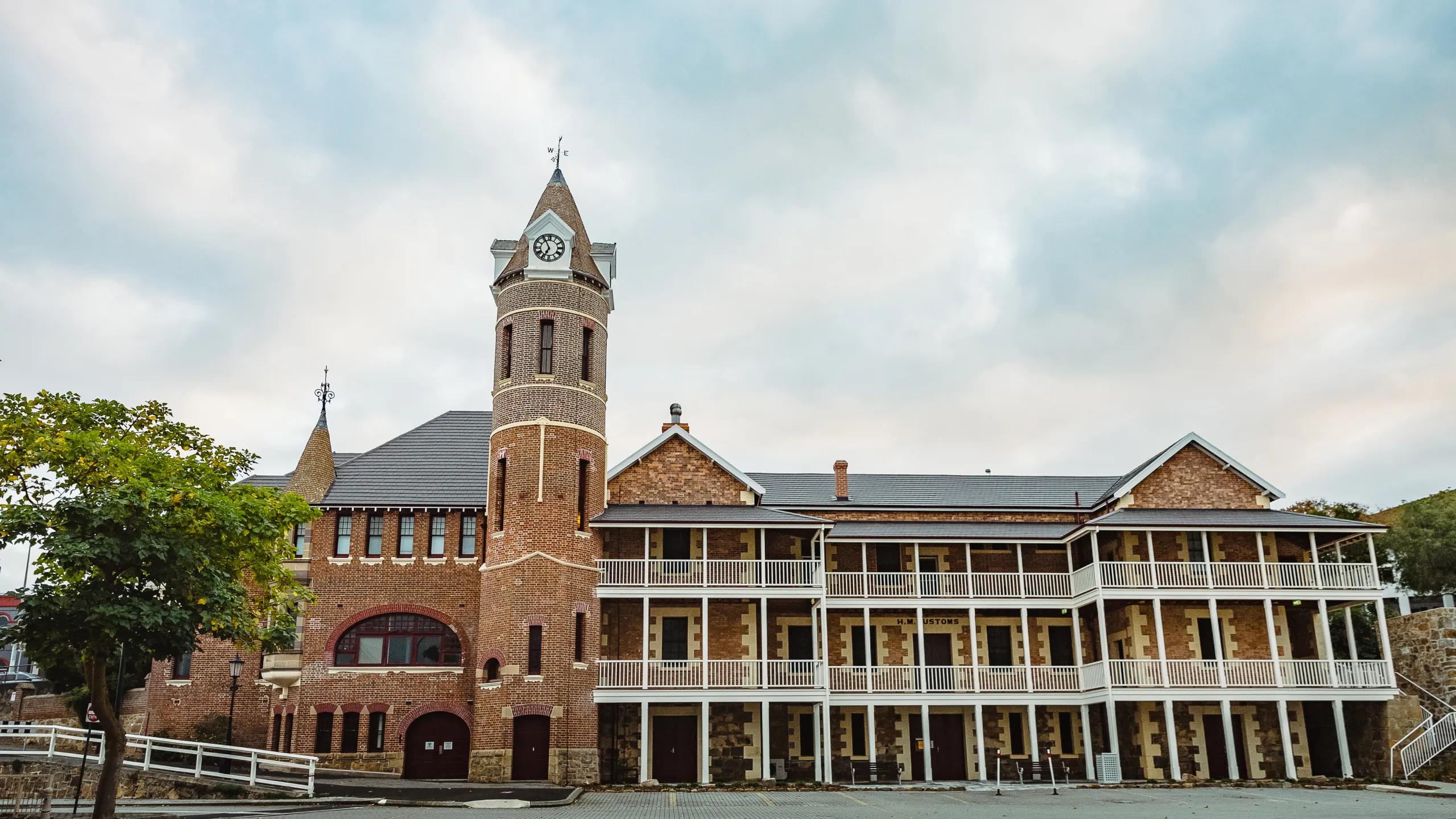 A photo of a large old fashioned building with a tower in the middle, a clock at the top.