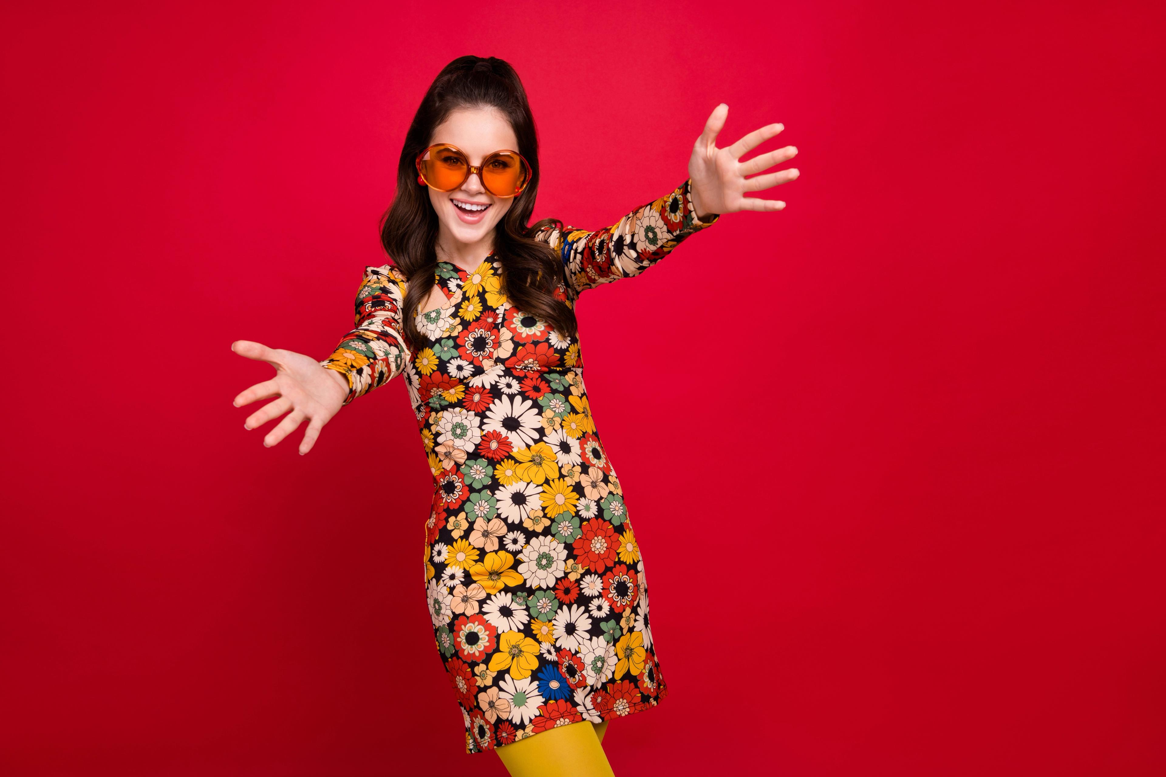 Woman dressed in a retro seventies dress and large sunnies.