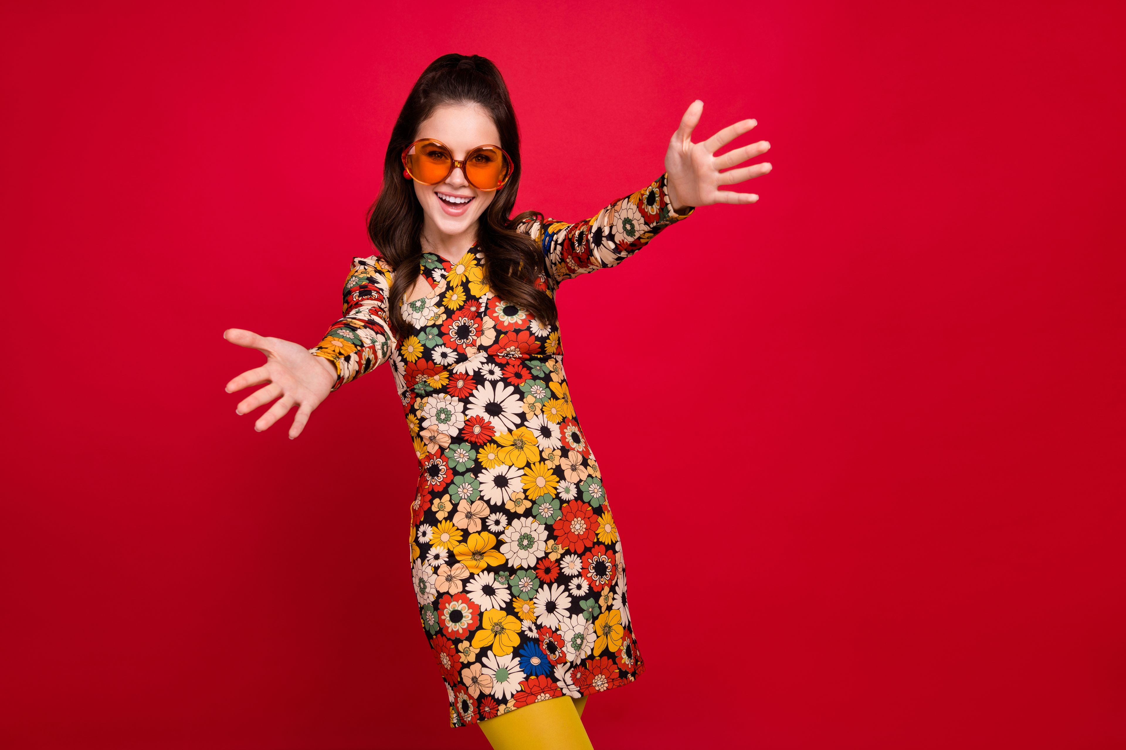 Woman dressed in a retro seventies dress and large sunnies.