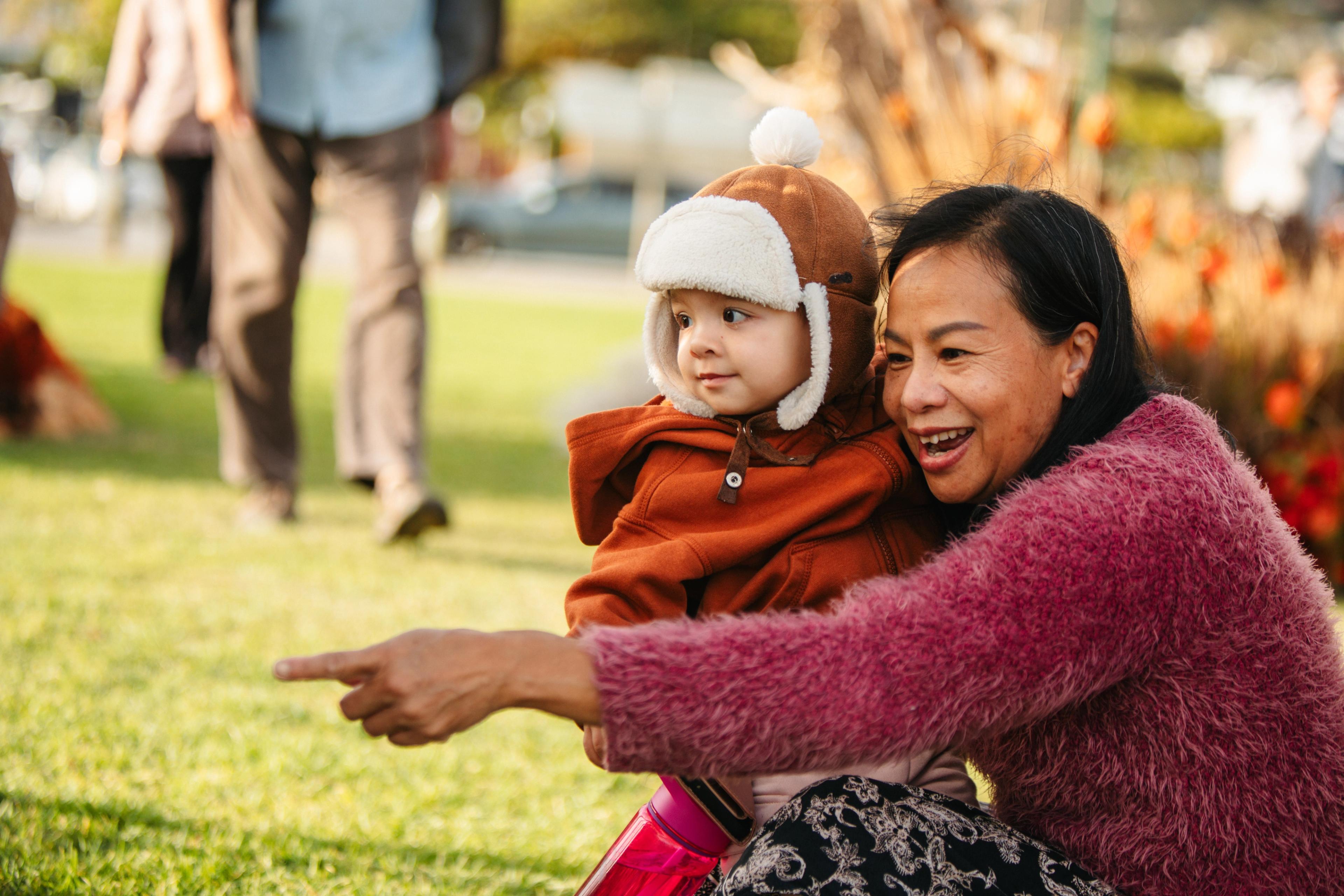 A mother and son crouch and look at something unseen with expressions of wonder