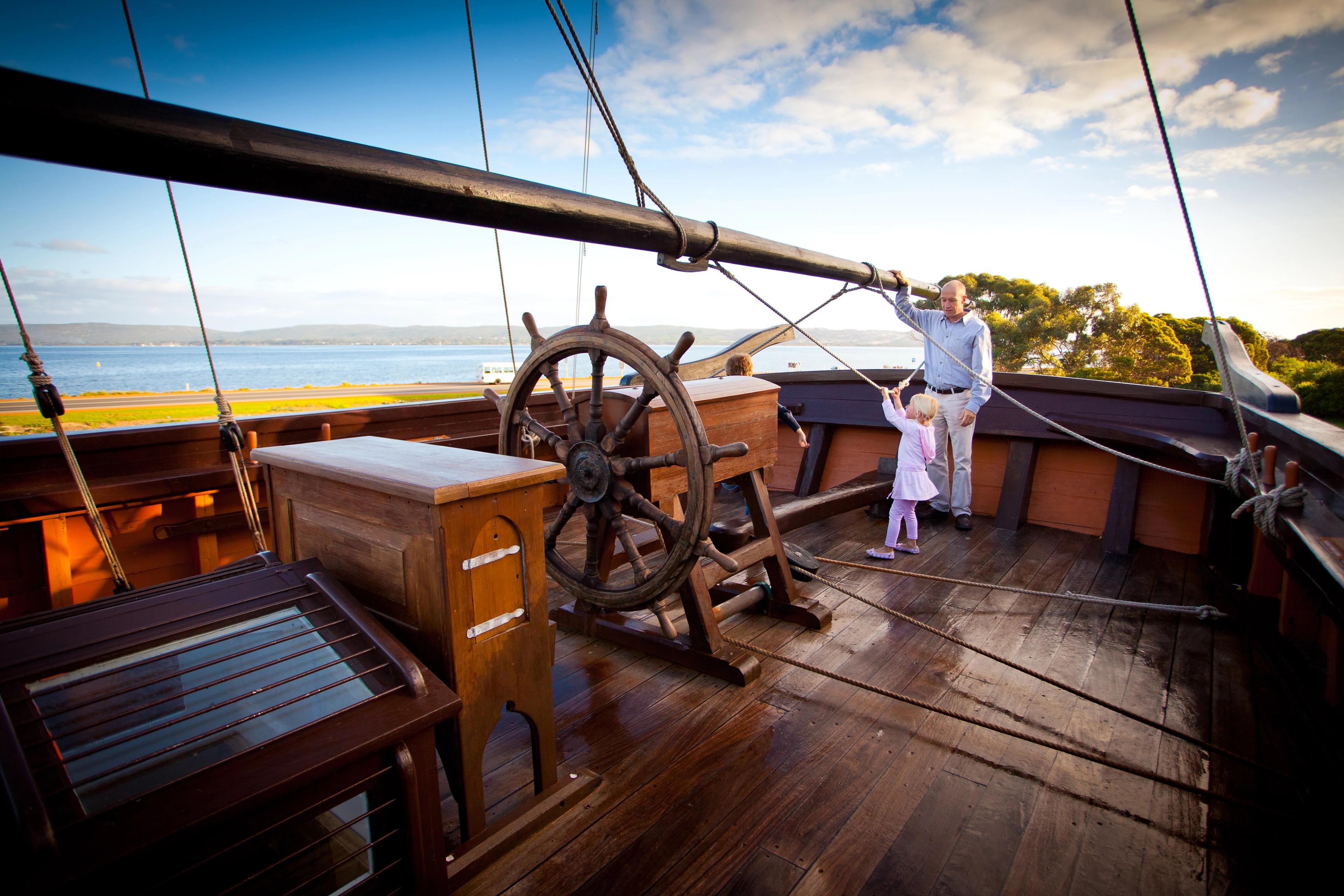 Father and daughter stand onboard the Amity. 