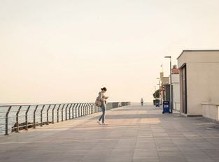 Un lungomare al mattino, con una persona che cammina in lontananza.