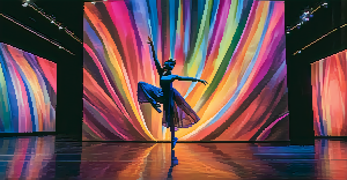 A dancer in a flowing costume performs on stage, surrounded by colorful projections that shift with their movements, creating a dynamic and immersive experience.