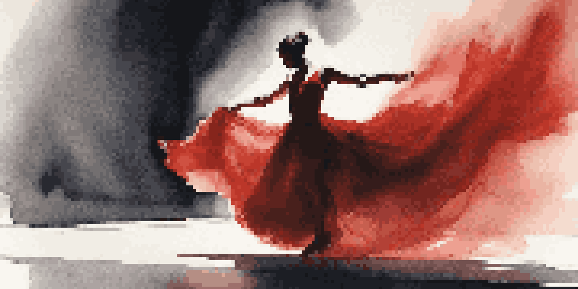 A contemporary dancer in a flowing red dress performing on stage under spotlight, with a dark background.