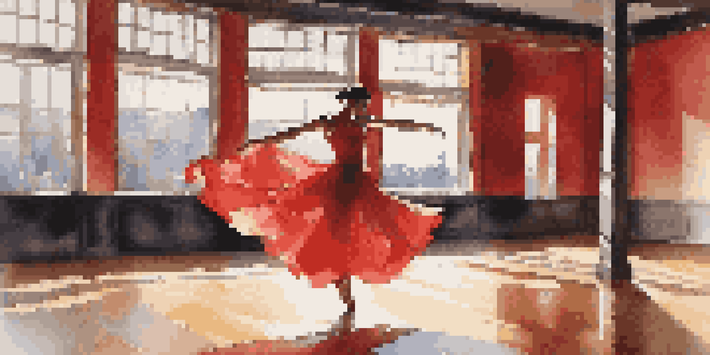 A female dancer in a red dress mid-leap in a dance studio with mirrors and sunlight streaming through windows.