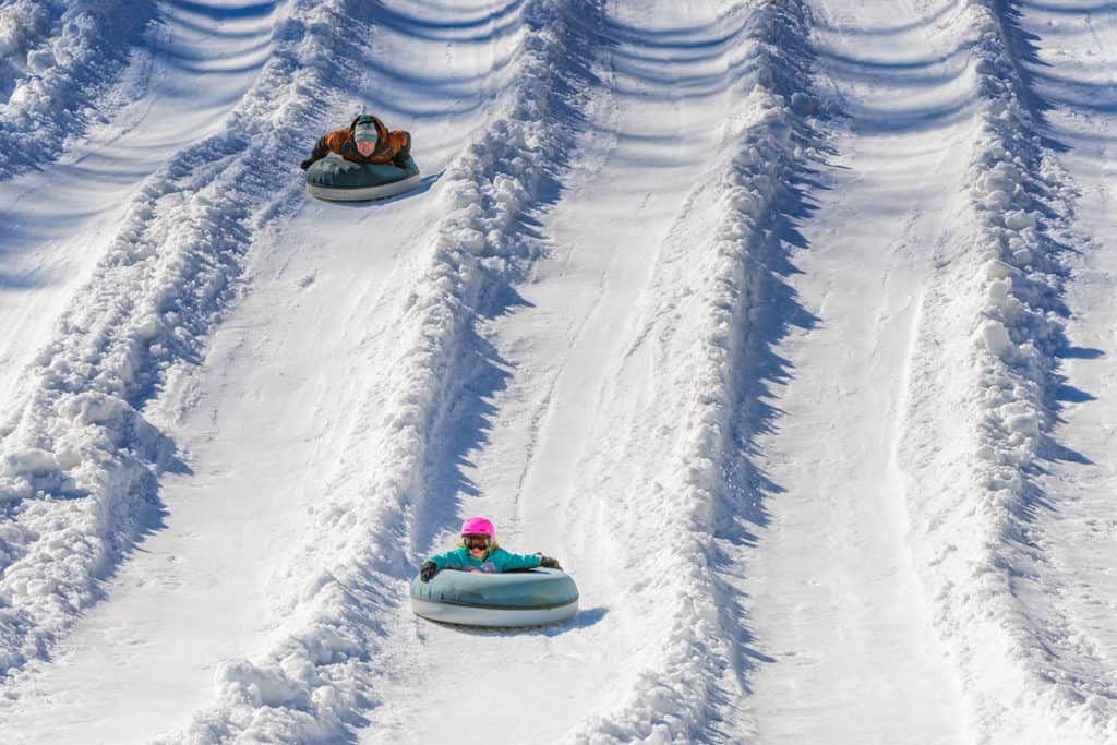 A father and daughter enjoying a snow tubing run at Tube World in Maggie Valley, North Carolina.