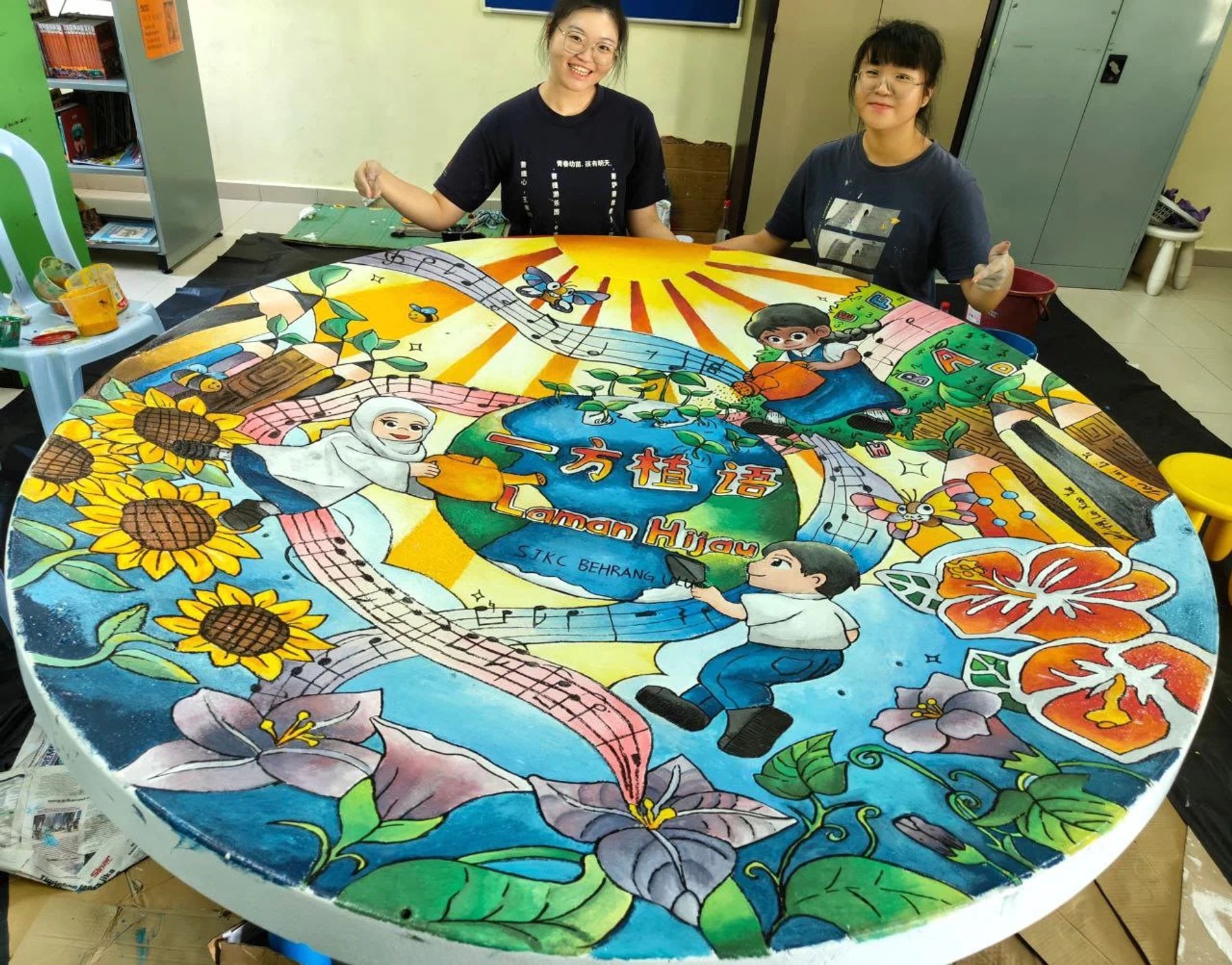 Two artists painting a circular community mural filled with local scenes