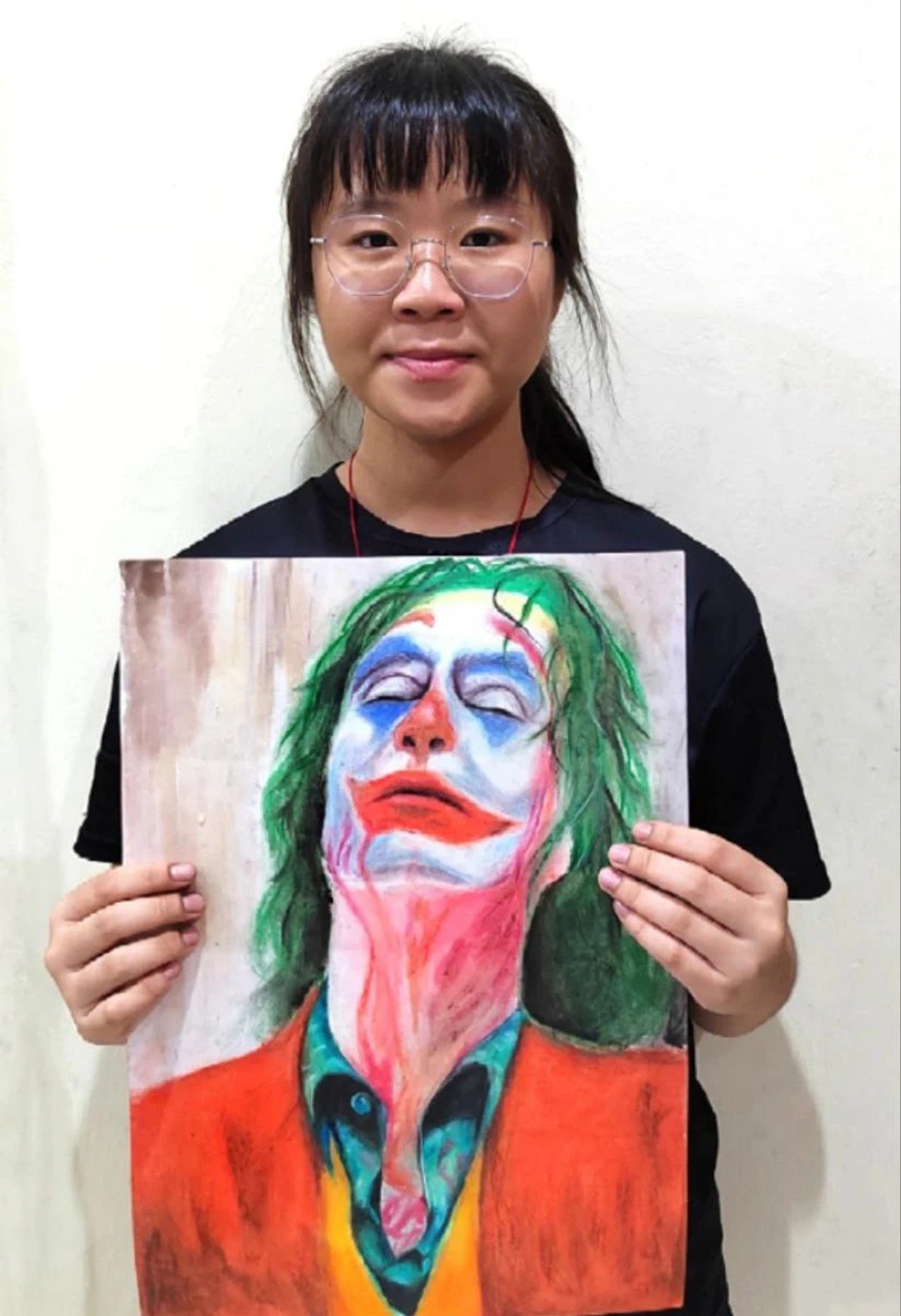 Student holding a dramatic painted character portrait
