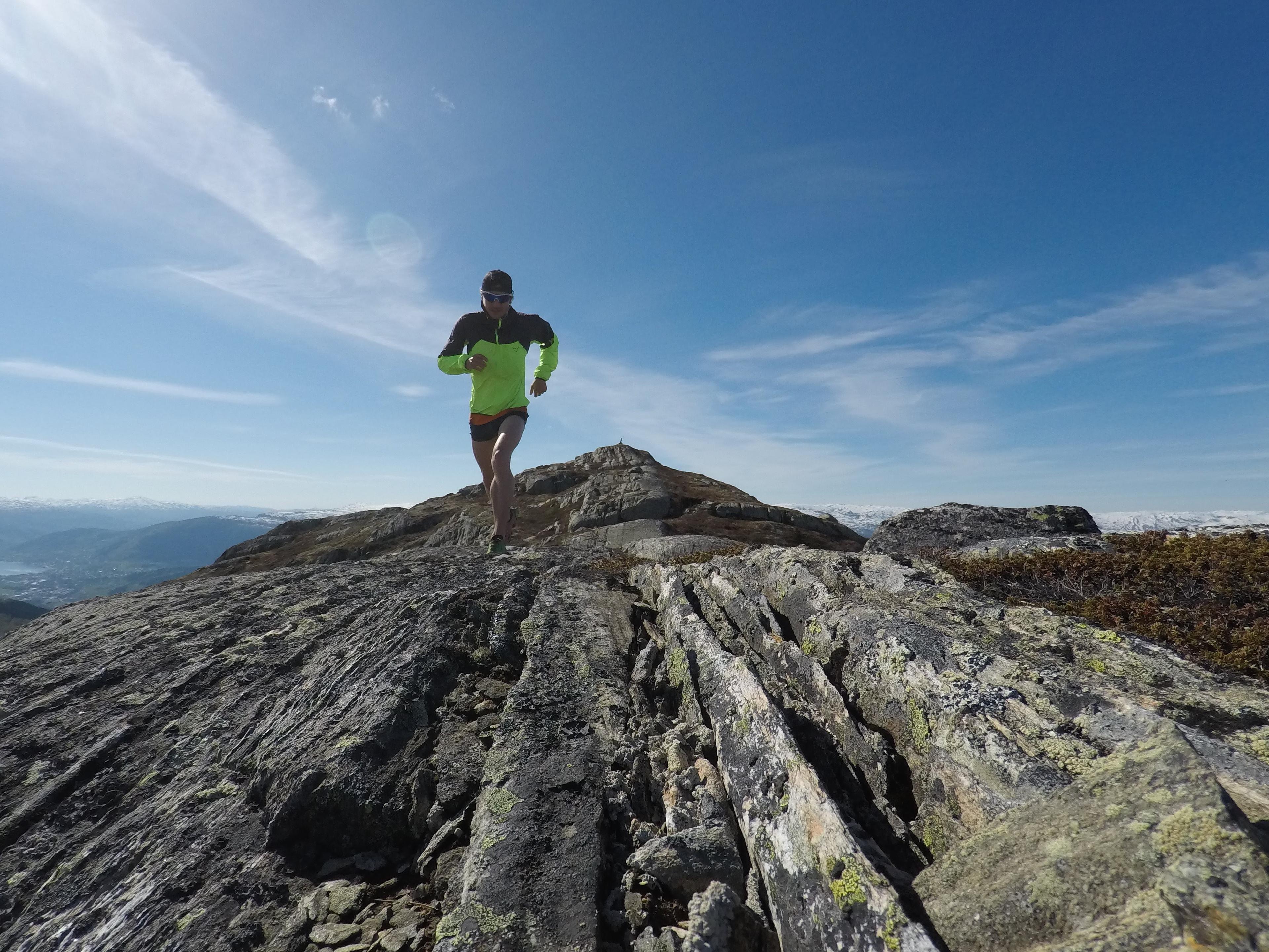 Person som springer på fjellet en sommerdag med flott utsikt.