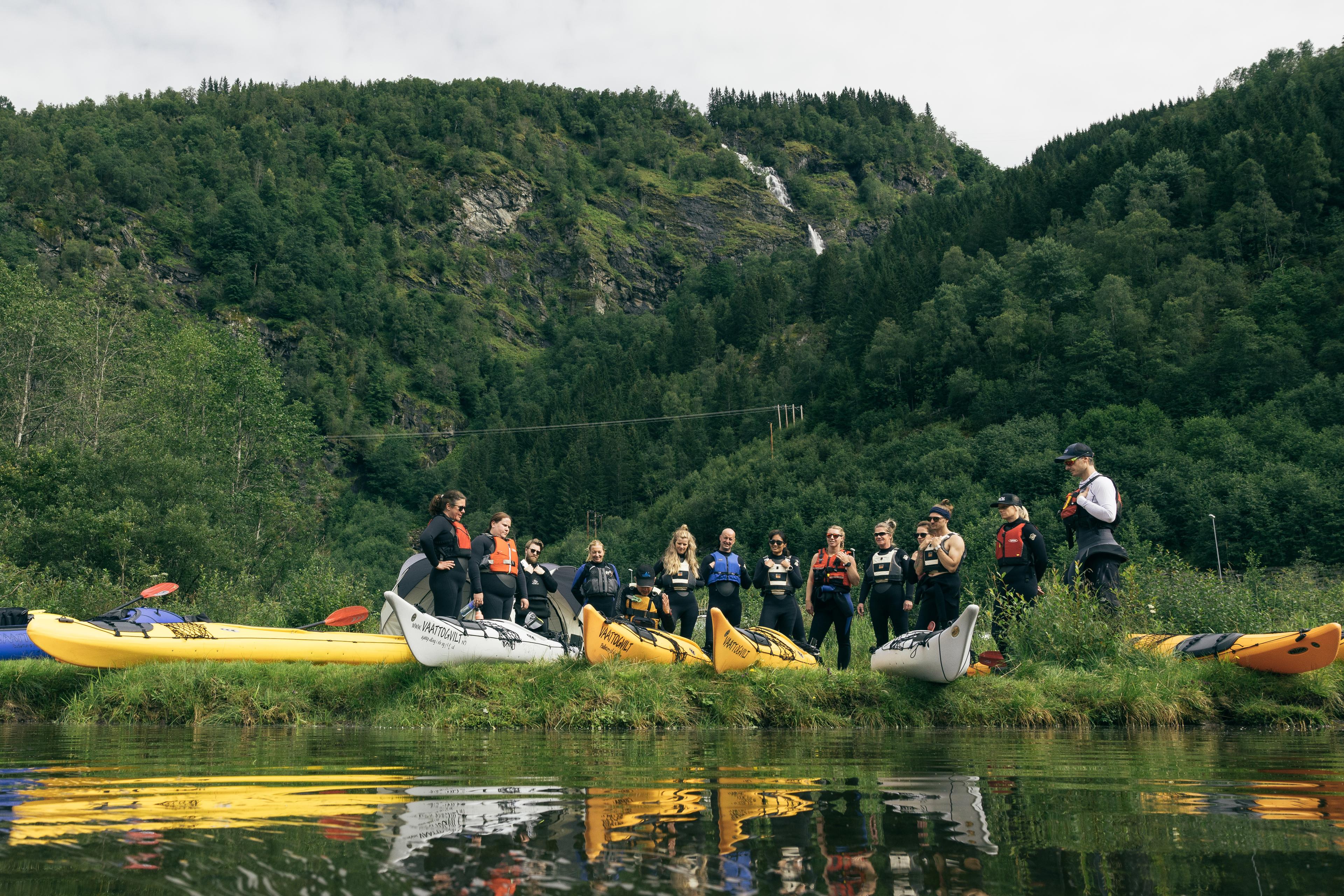 Ei gruppe på kajakkurs får innføring i kajakkpadling, først på land.