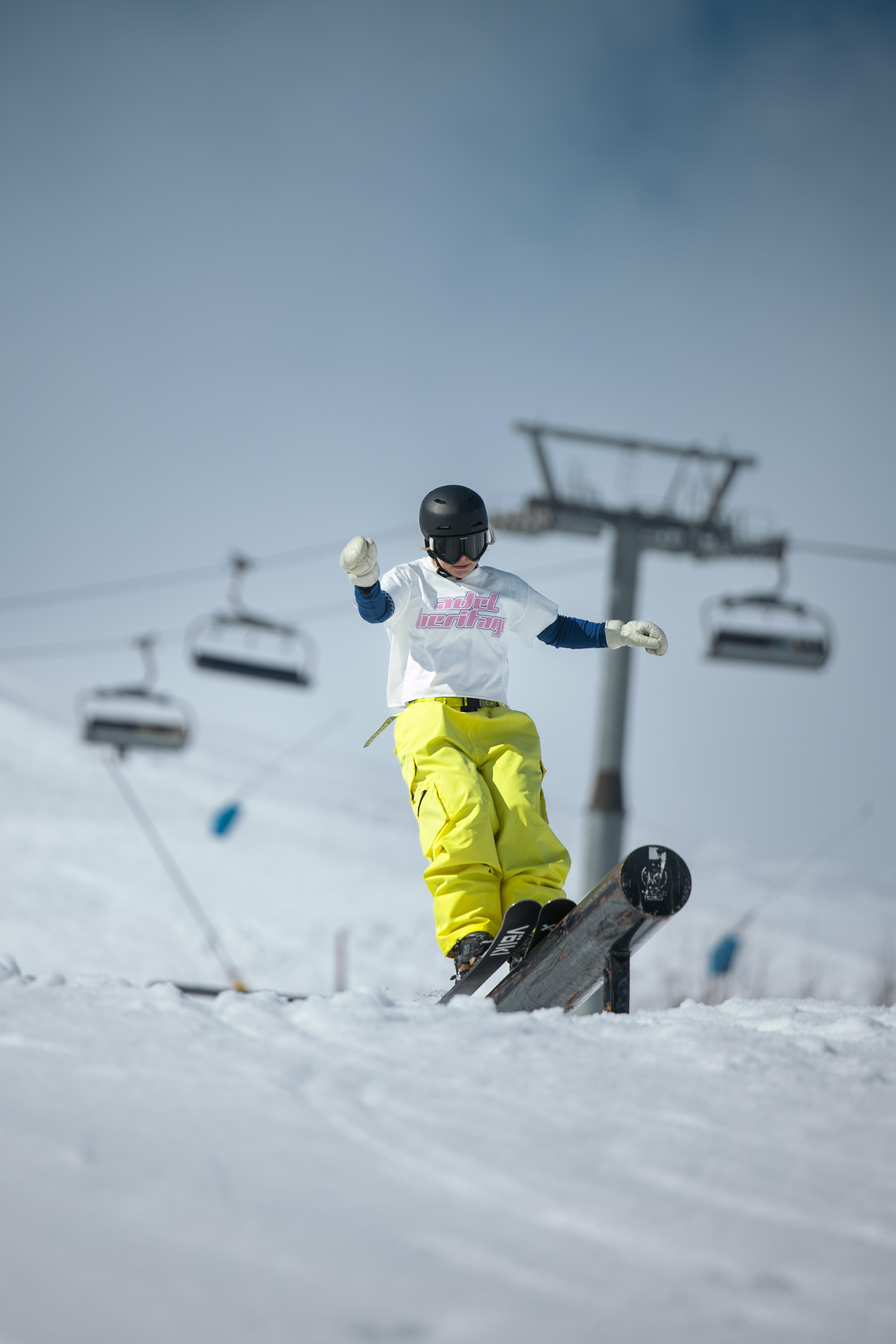 A young boy is snowboarding down a hill with the ski lift in the background