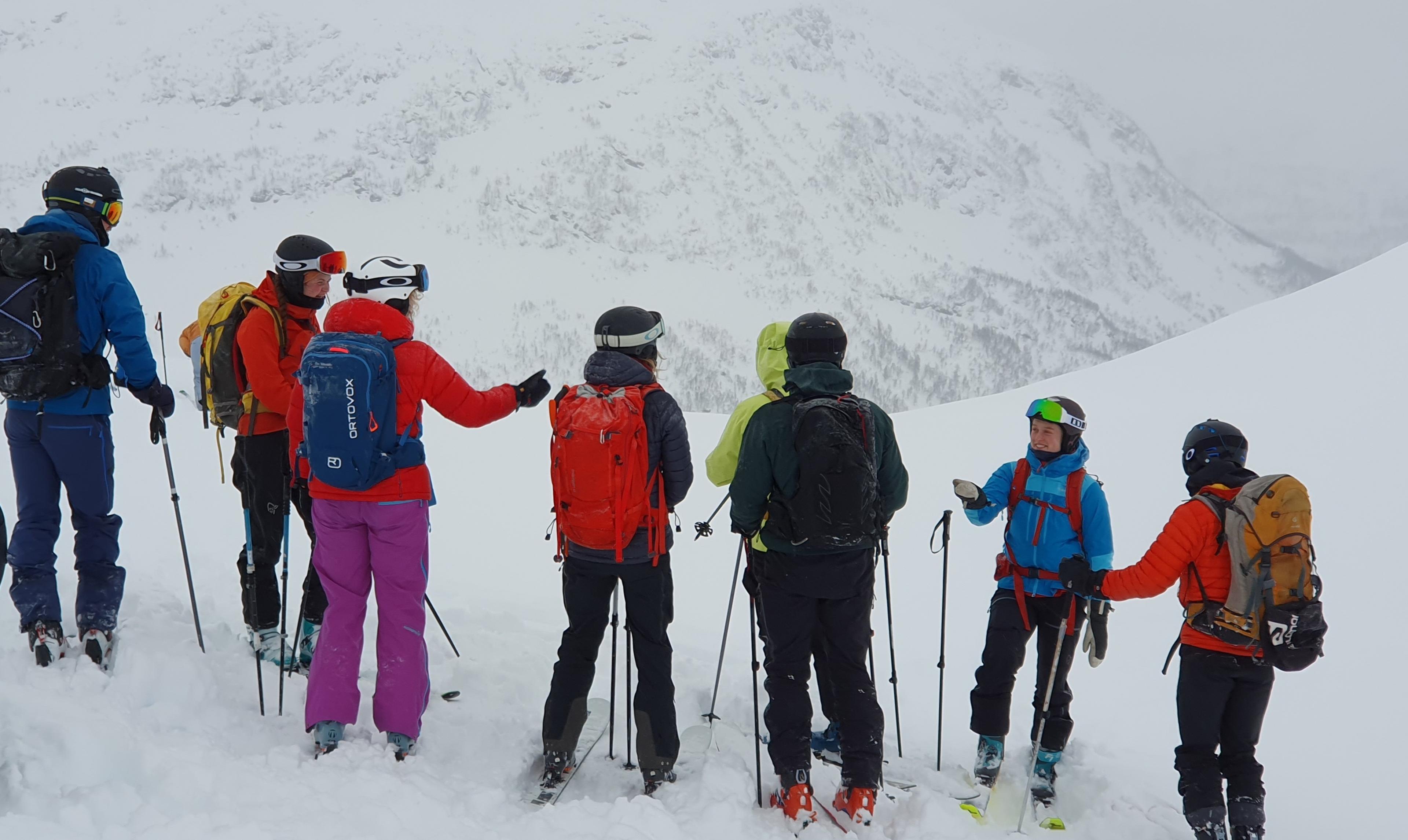 En gjeng i fargerike skiklær står i en klynge og snakker