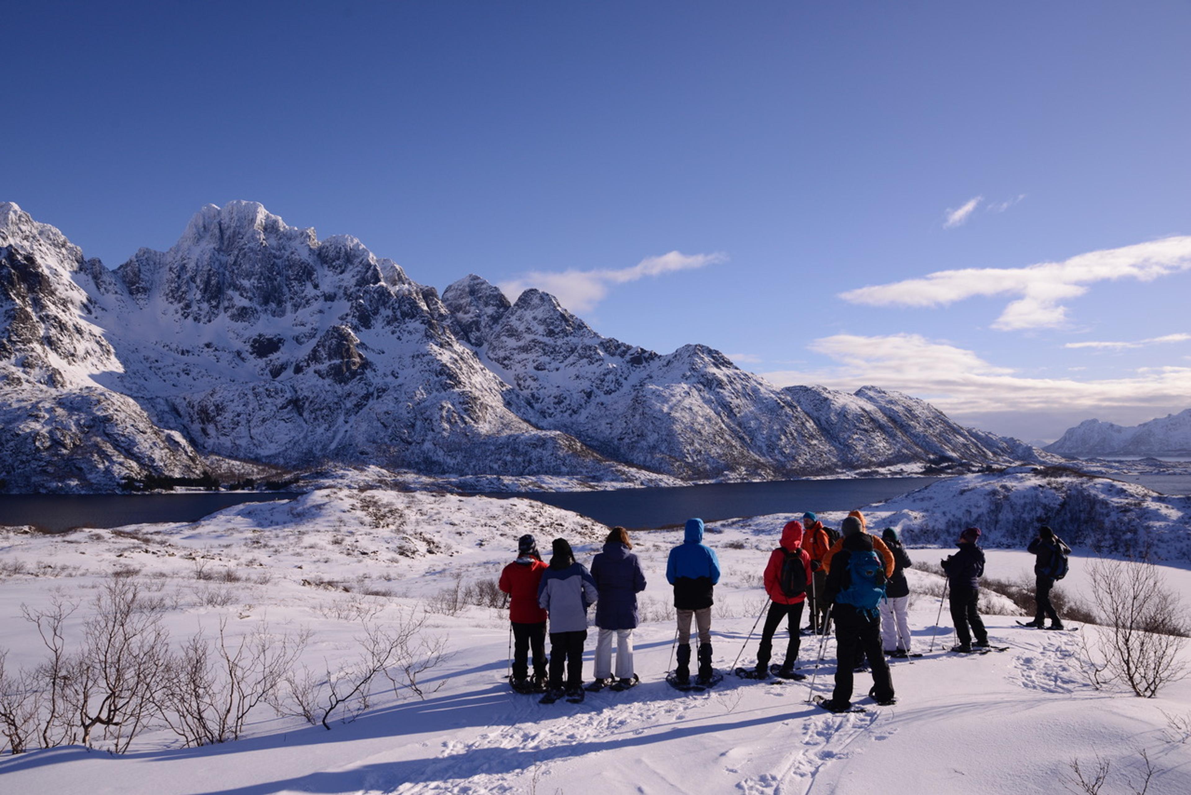 Explorers on snowshoes take in the spectacular snow-covered mountains and fjords.