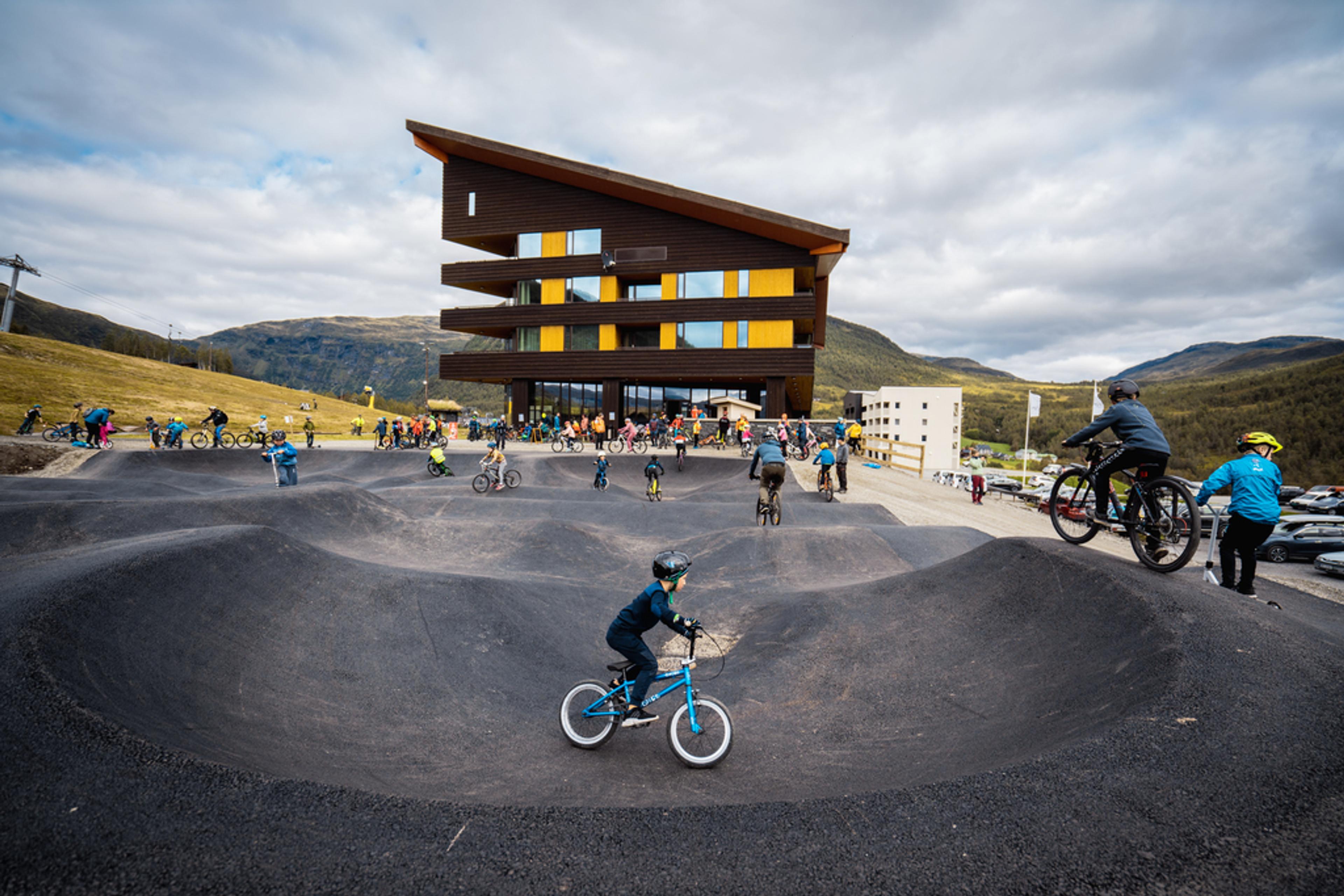 Store og små barn på sykkel i pumptracken utenfor Myrkdalen hotel.