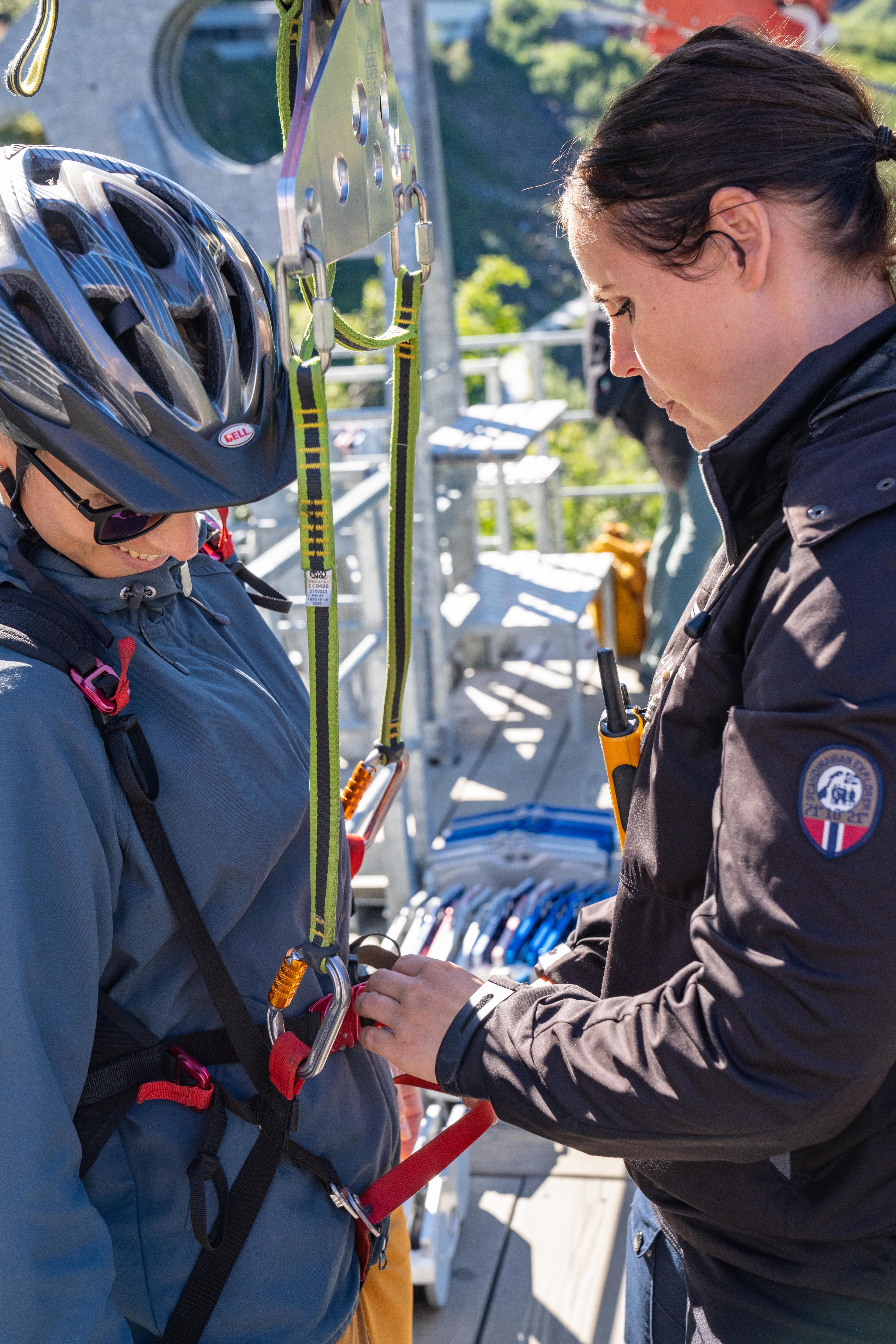 Un client est aidé pendant que son harnais est attaché à la tyrolienne.