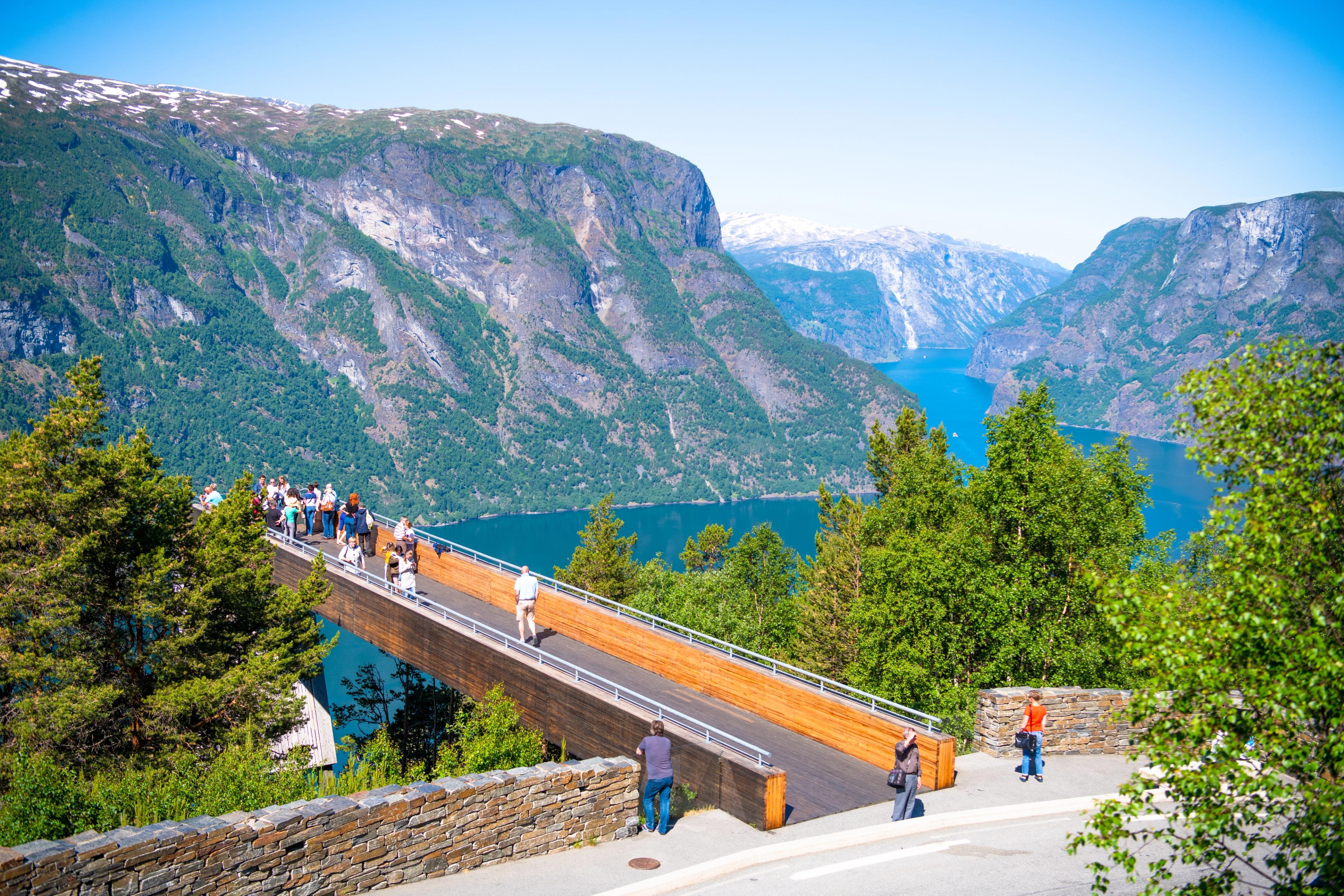 Turister ser utover fjorden fra Stegastein i sommervær