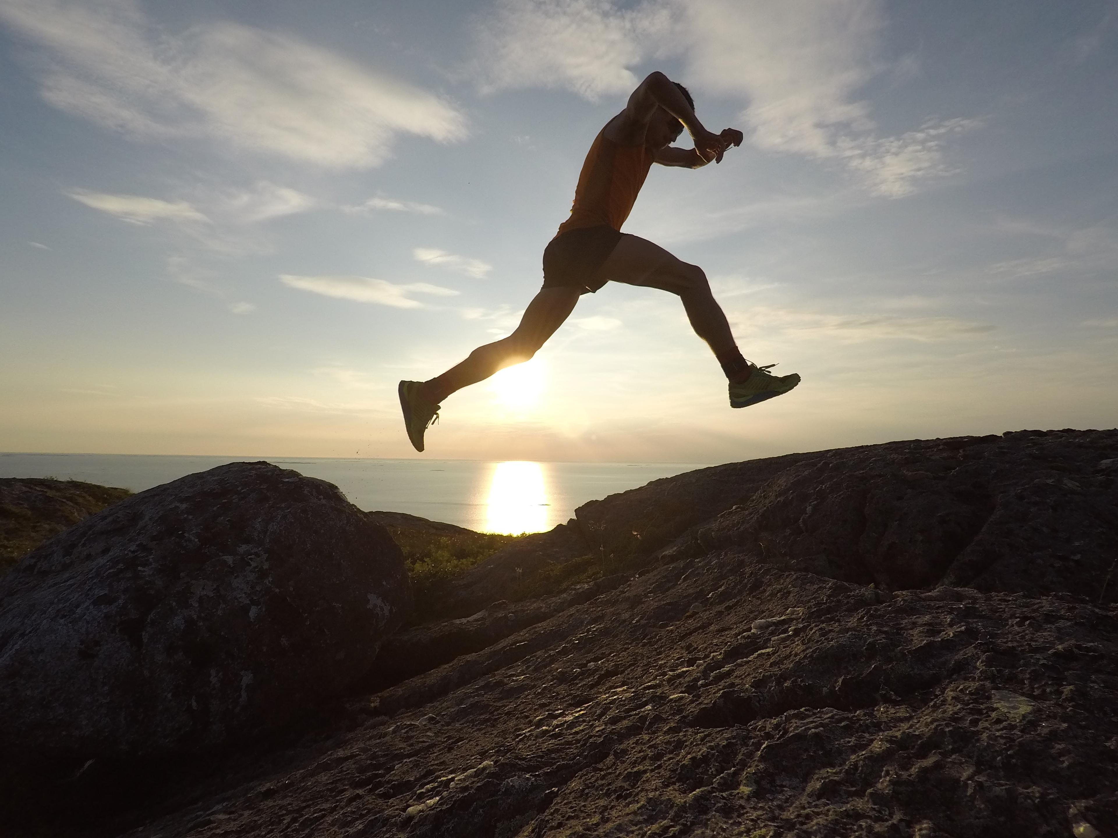 Gutt hopper over solnedgangen på fjellet.