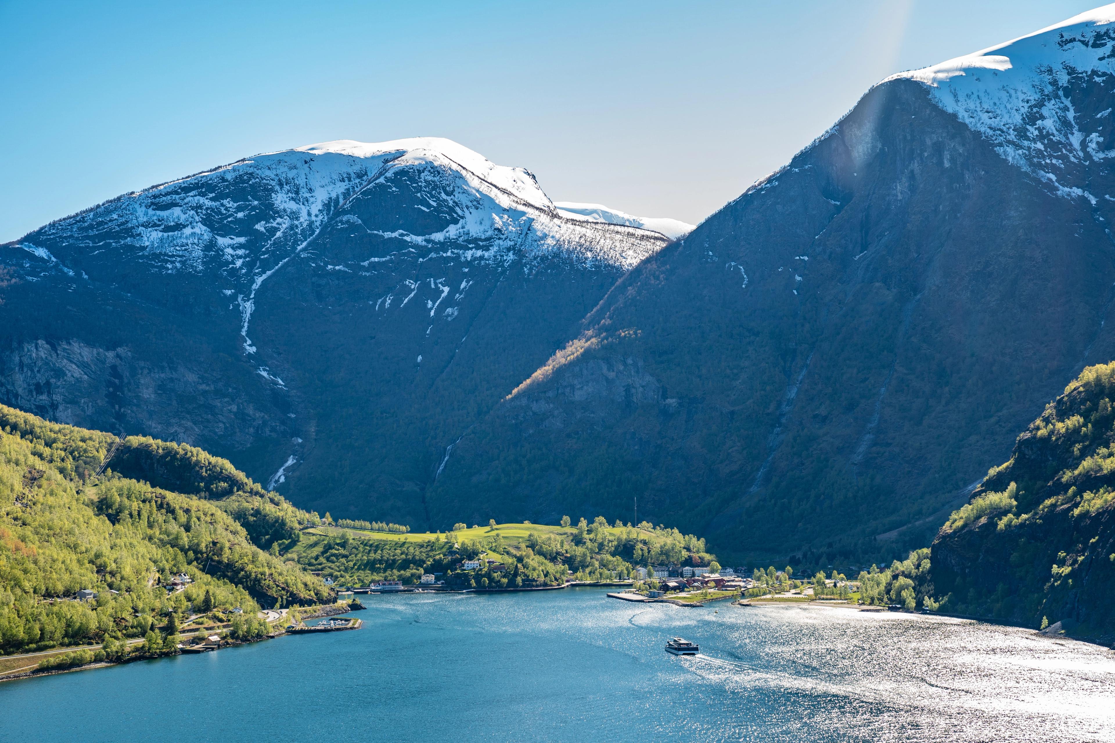 En katamaran seiler inn mot havnen i Flåm på en fin vårdag.