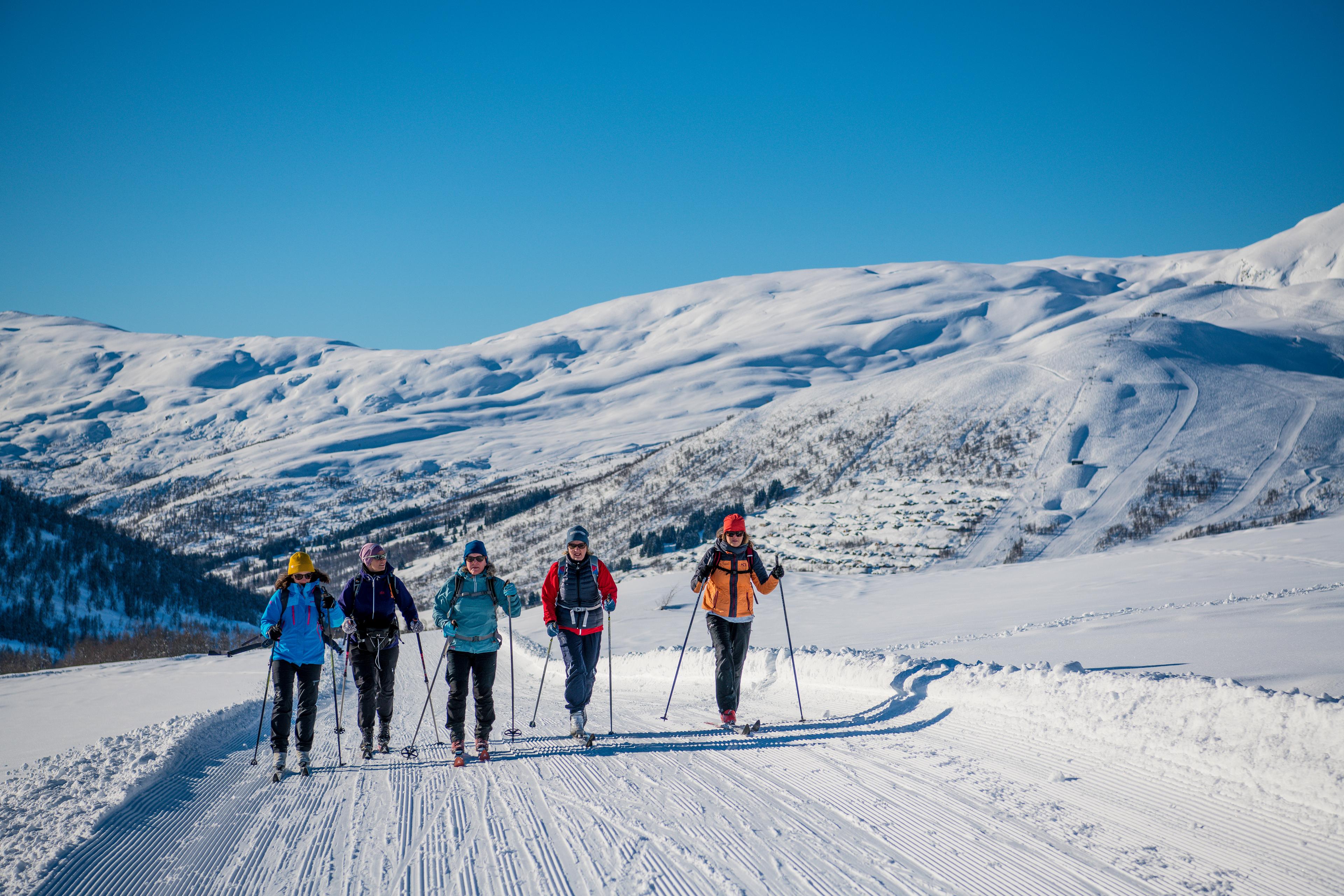 A group of people go cross-country skiing on a groomed trail