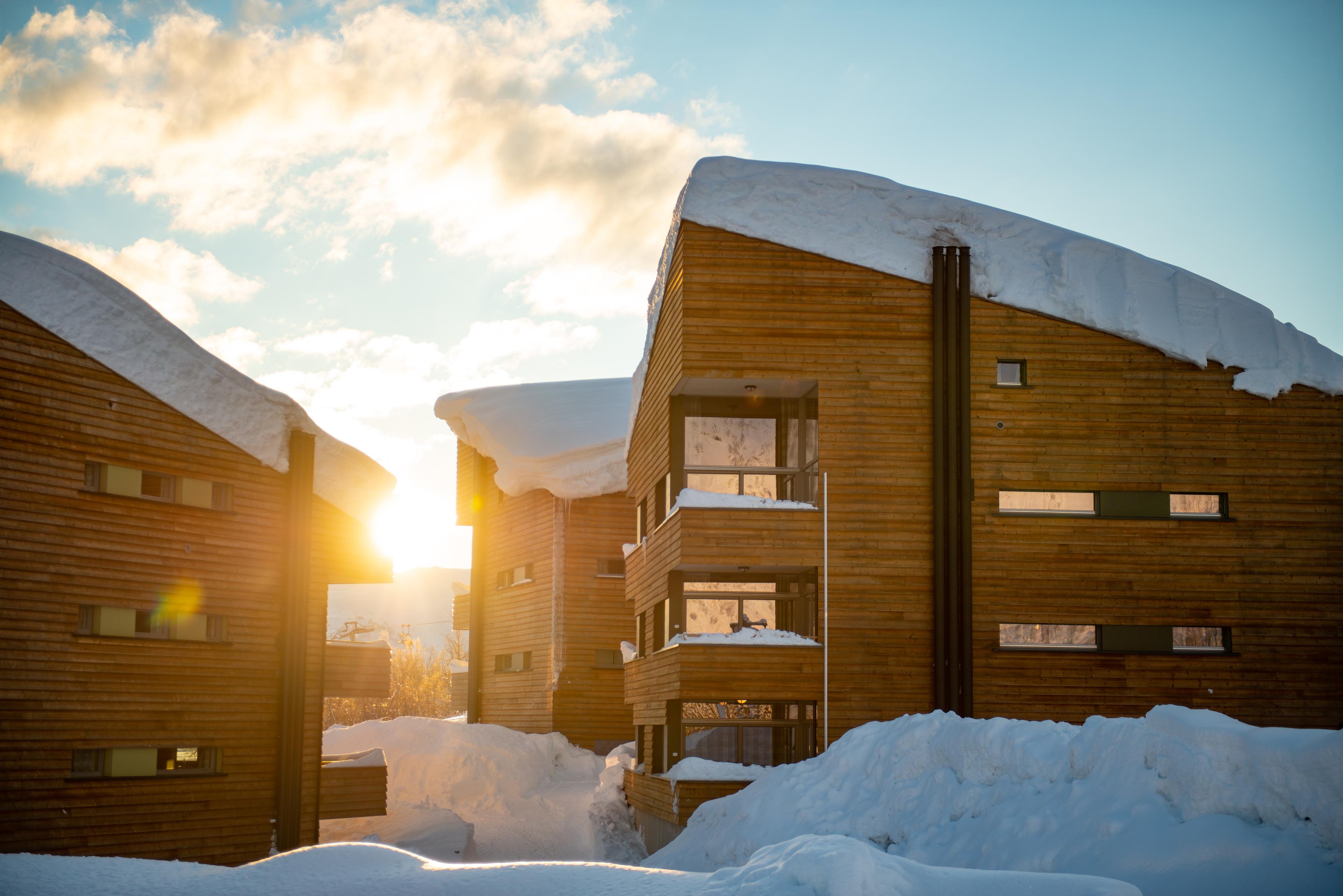 The sun shines between snow-covered buildings