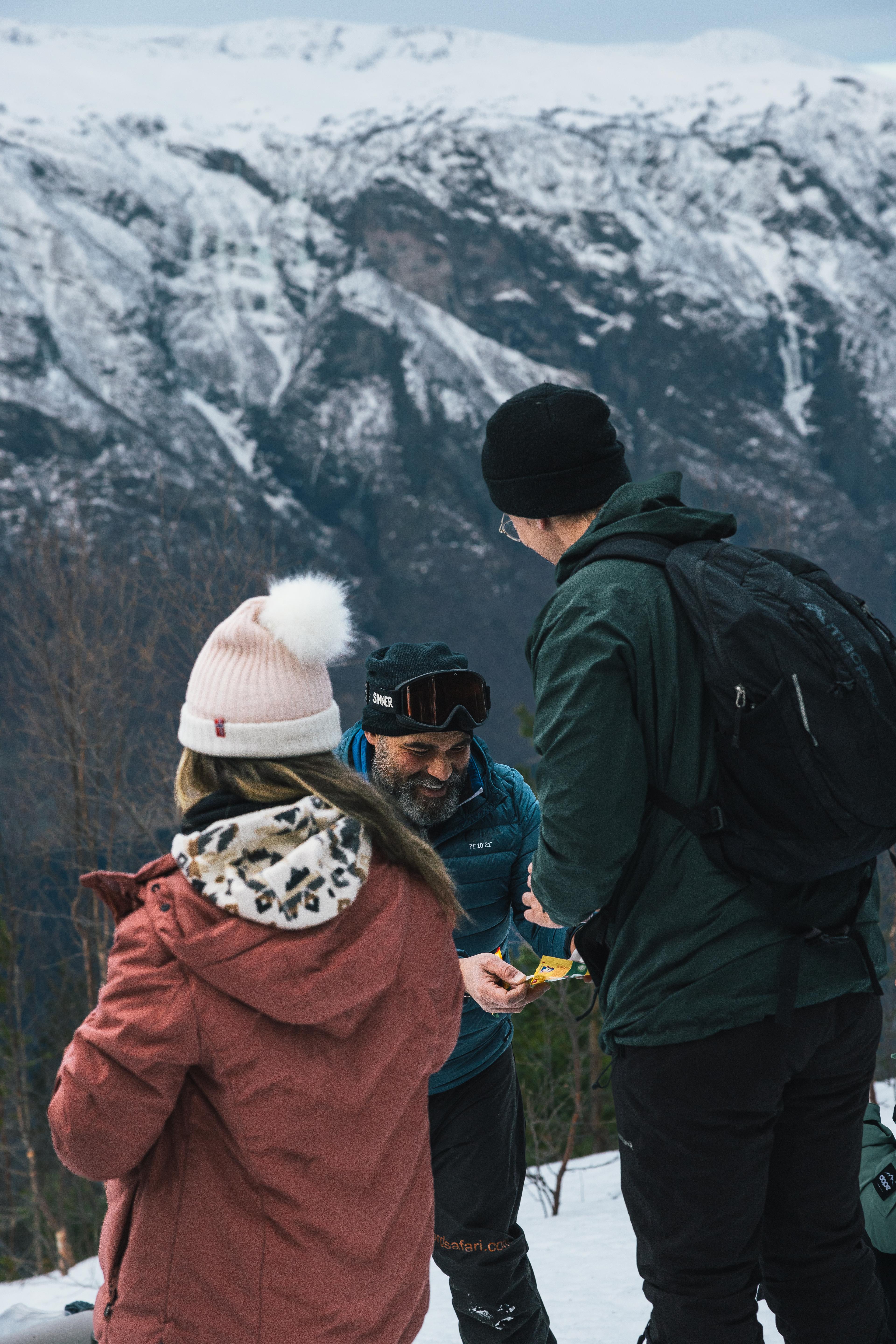 A guide hands out Kvikk Lunsj chocolate to guests on a snowshoeing trip.