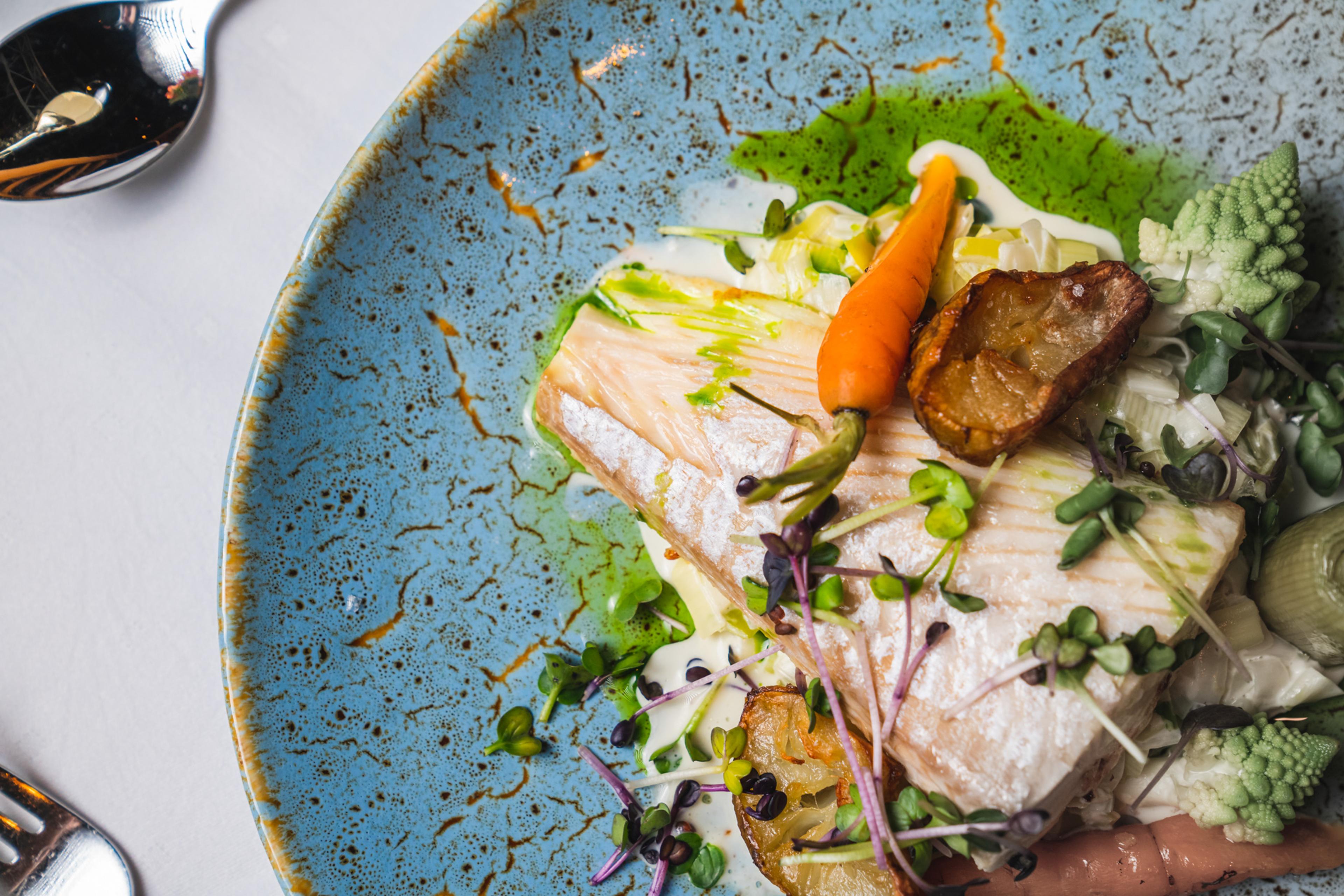 Ein Fischgericht auf einem Teller im Restaurant Arven des Fretheim Hotels.