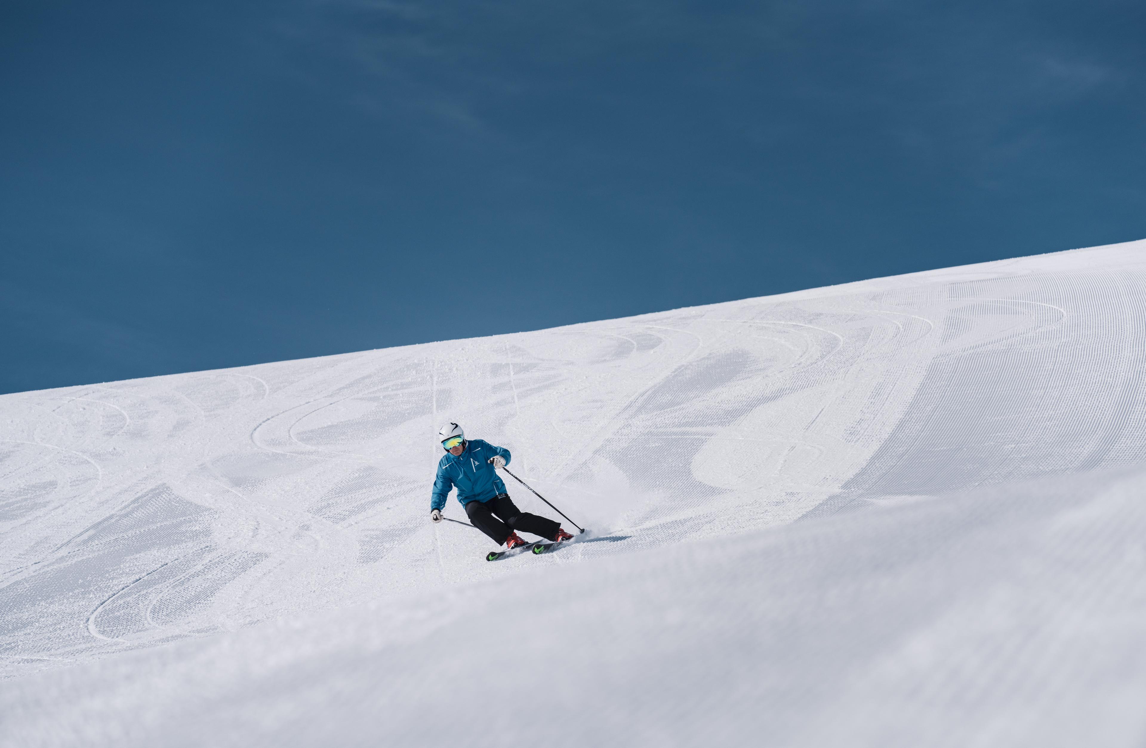 Slalåmkjører står ned bakken under blå himmel.