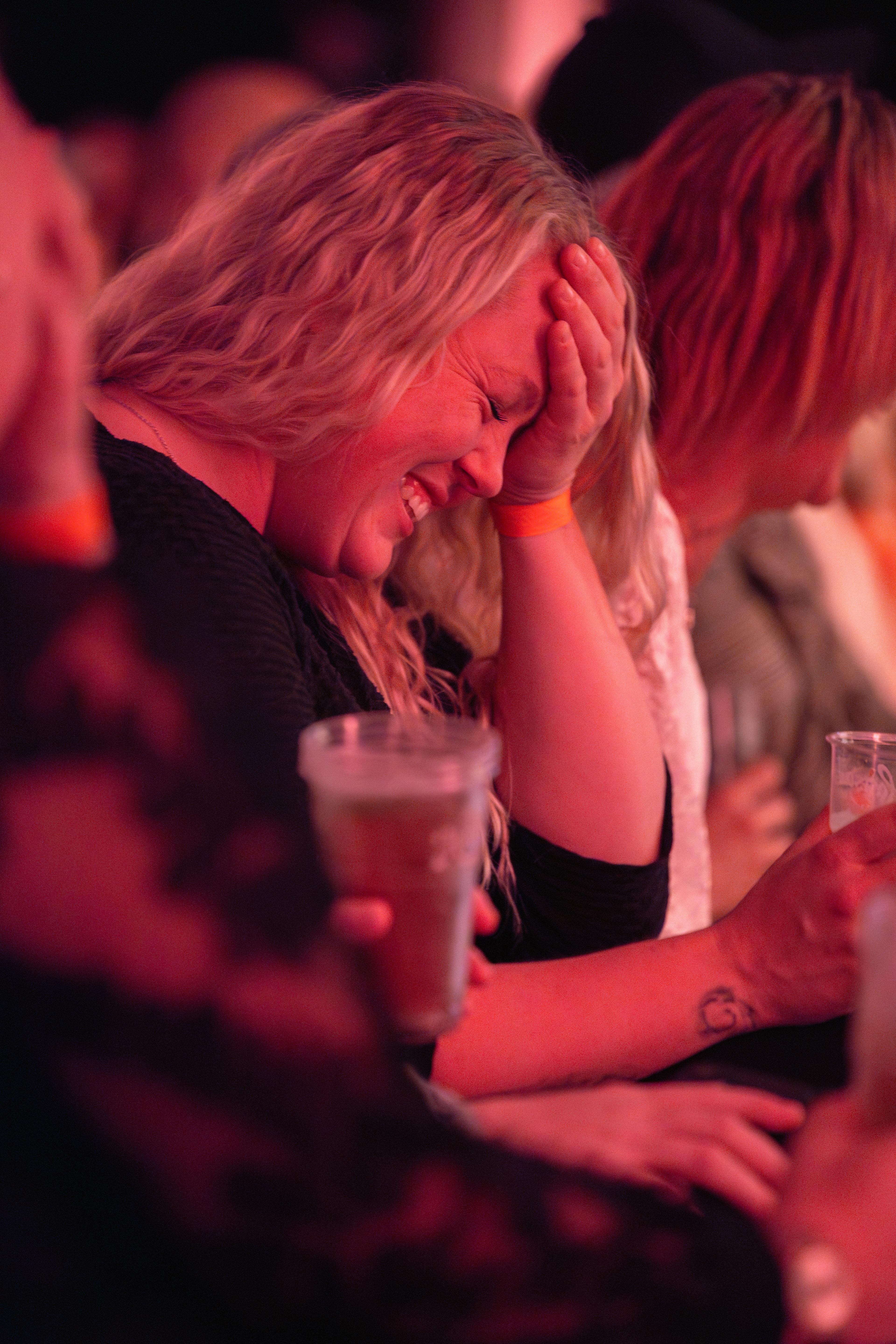 Kvinnne som ler og holder seg til pannen