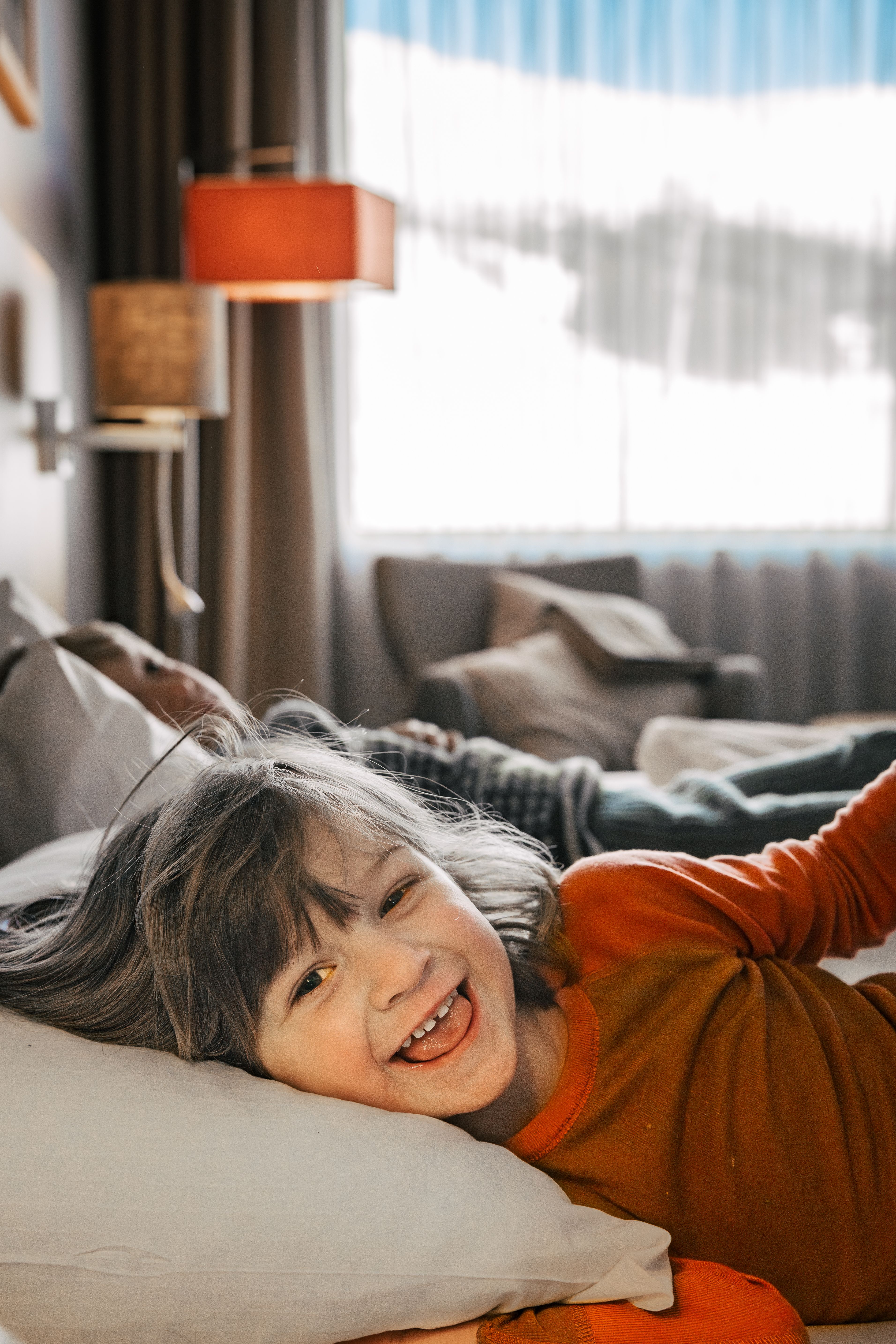 Barn som ligger i senga og ler