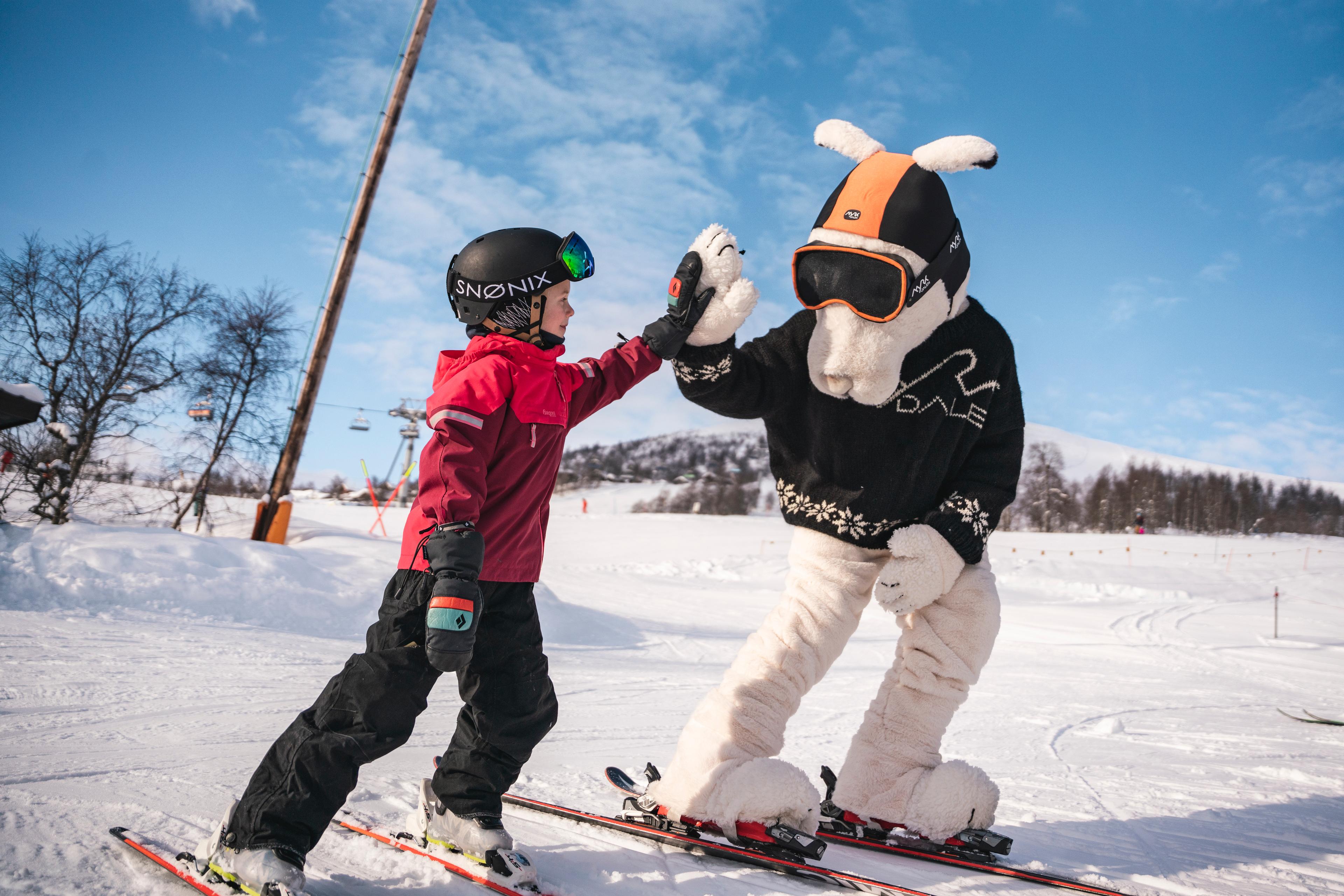 Et barn på slalåmski gir haren Finn en «high five».