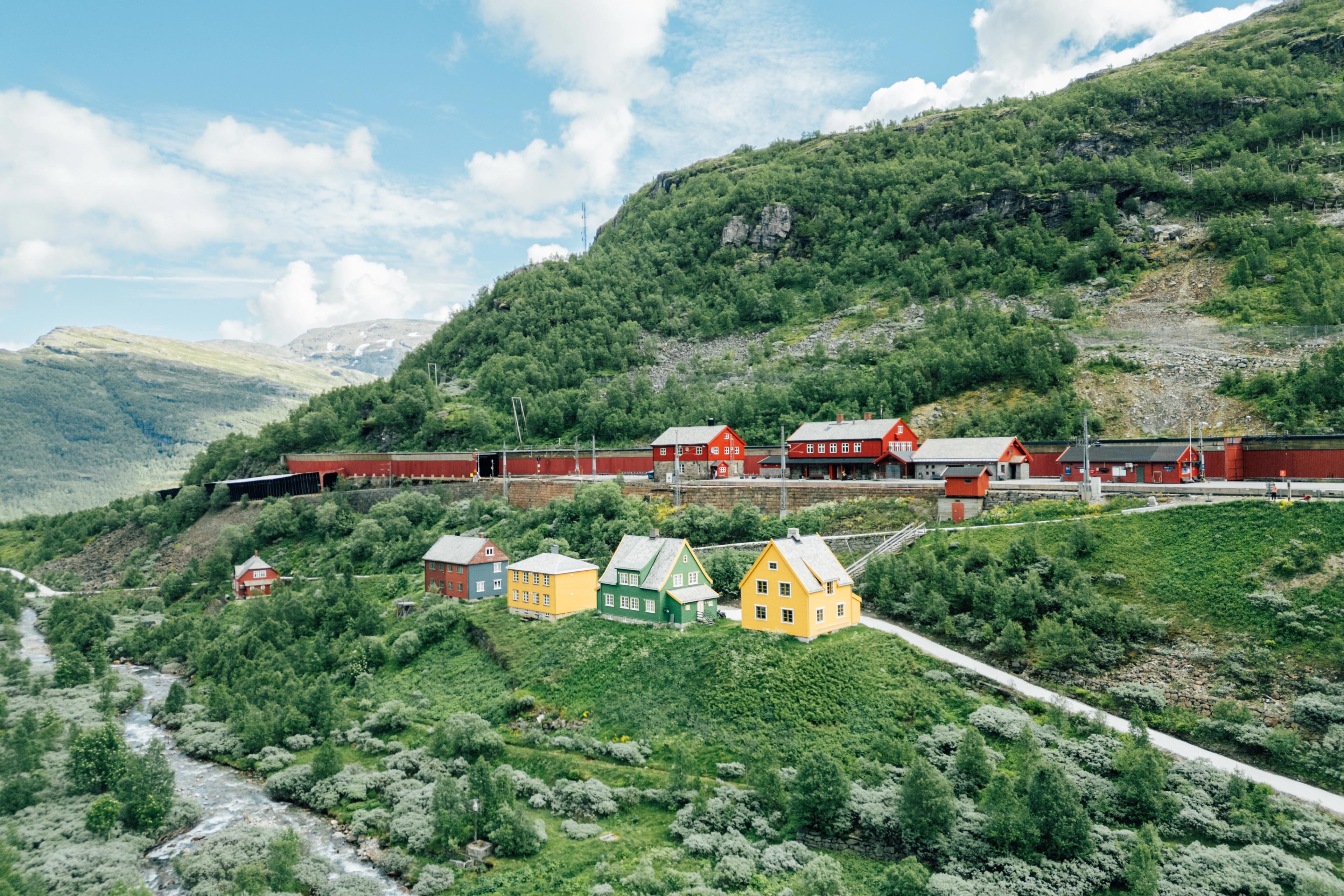 Ein Bahnhof im norwegischen Gebirge mit kleinen Häusern und viel Landschaft.
