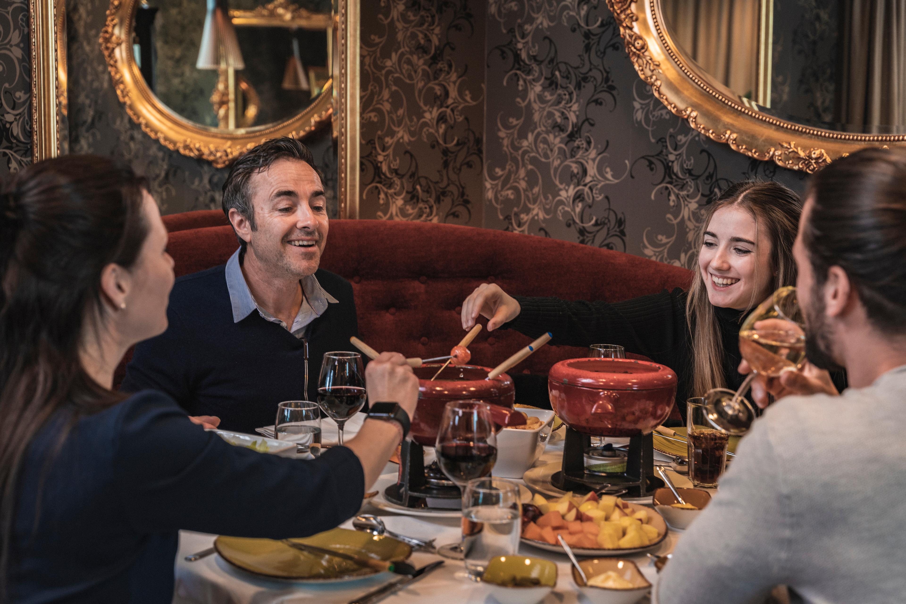 En vennegjeng koser seg rundt bordet med fondue og drikke på restaurant.