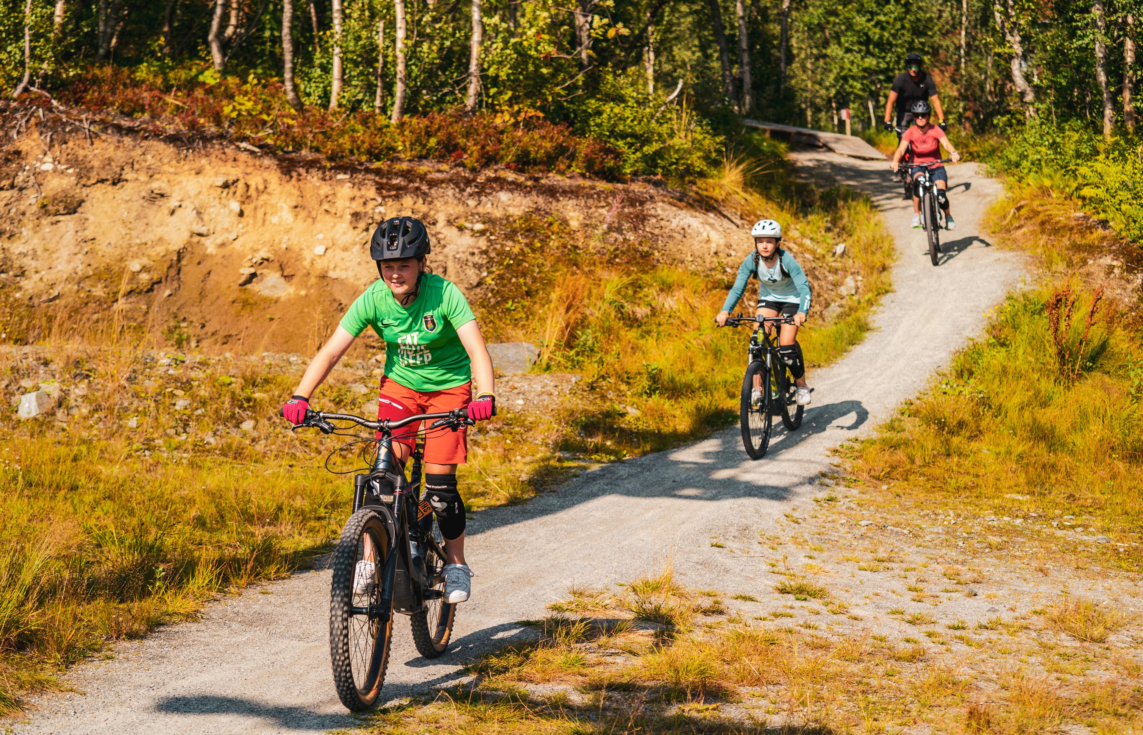 A family cycling down a gravel path in the forest.