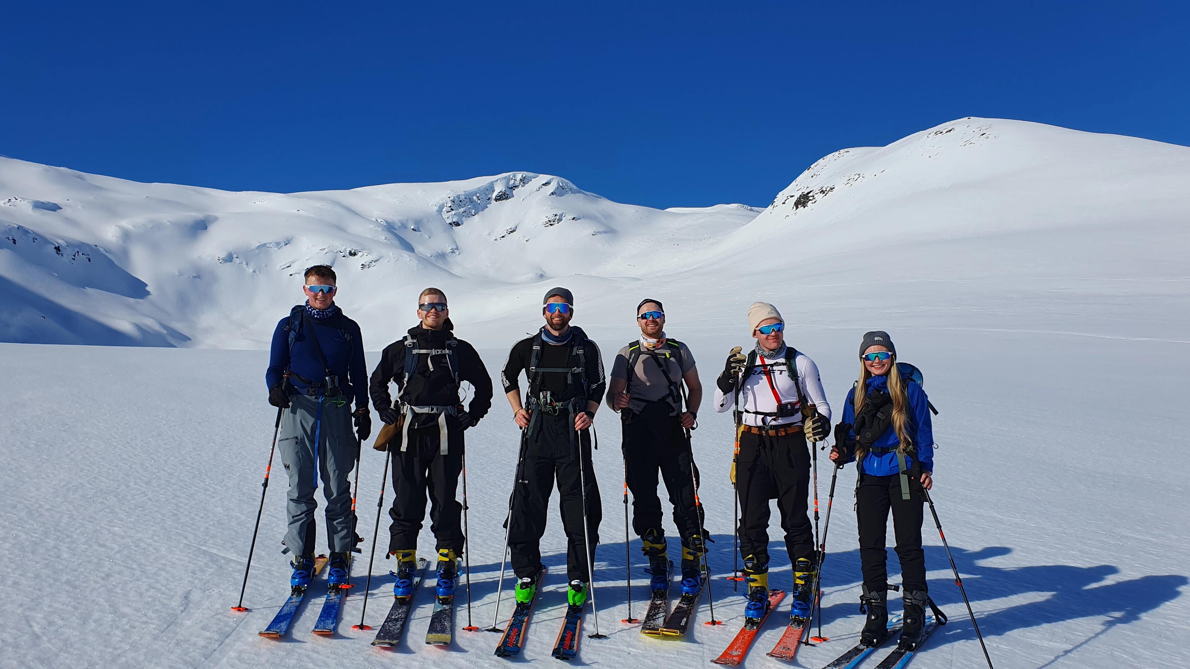 A group of ski tourers posing for the camera. Snow and blue skies.