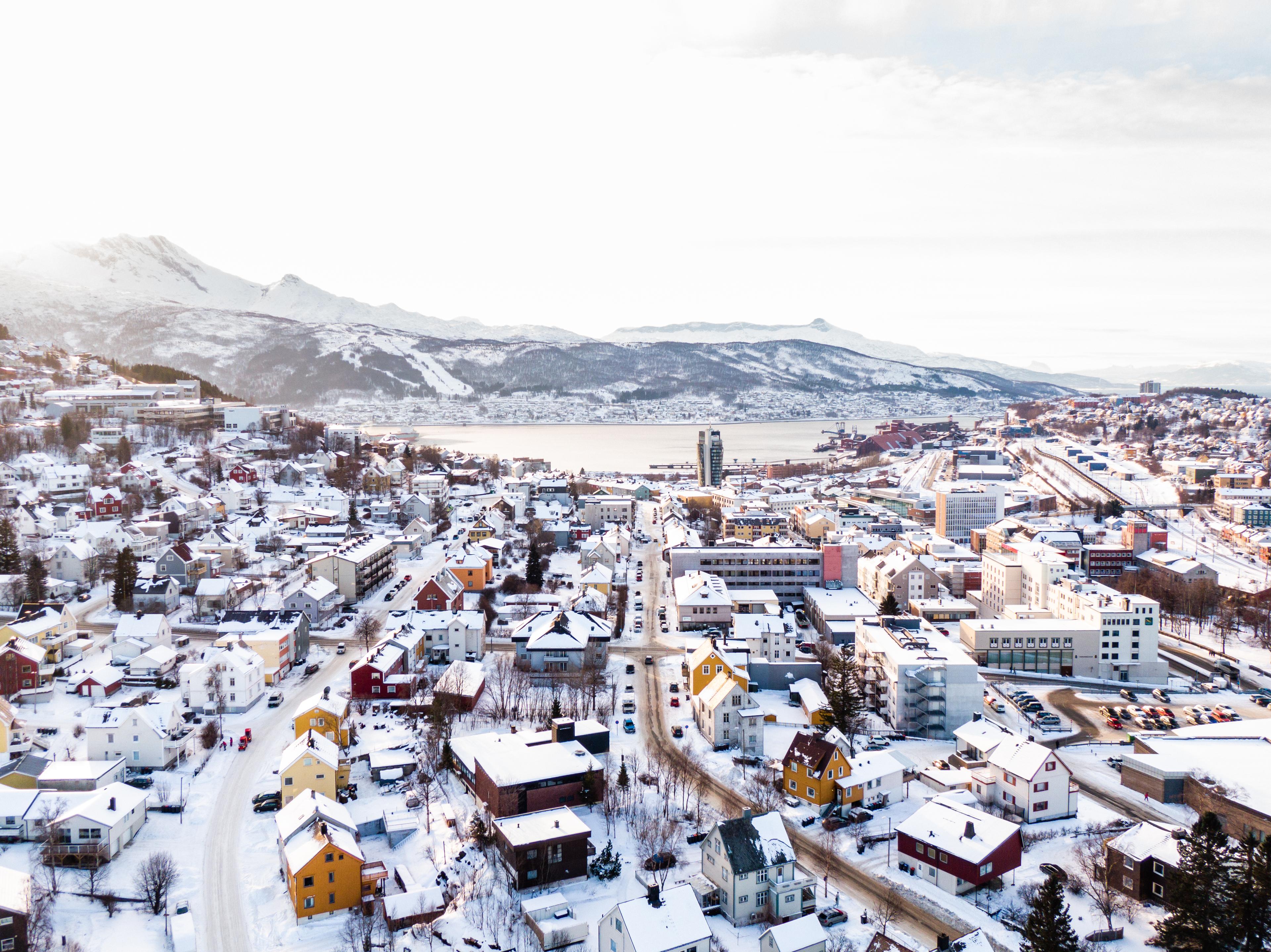 Vue de Tromsø sous la neige, avec des montagnes en arrière-plan.