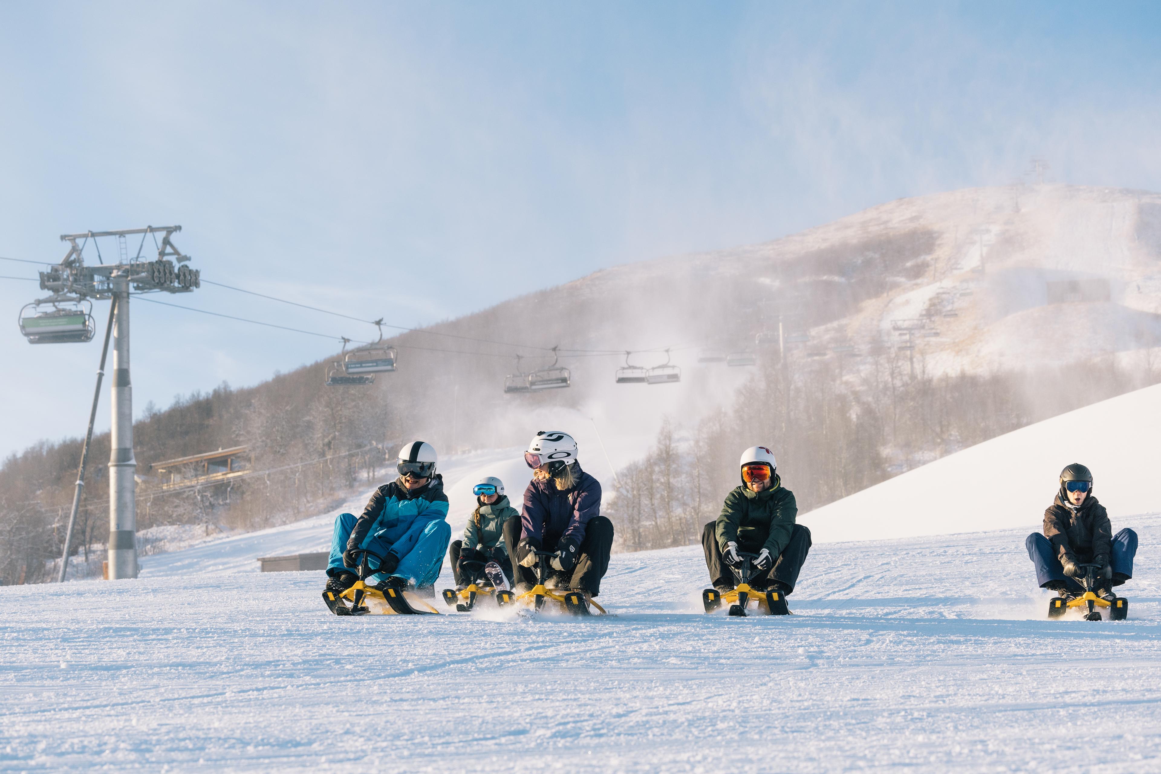 En gjeng aker ned slalåmbakken på snowracer.