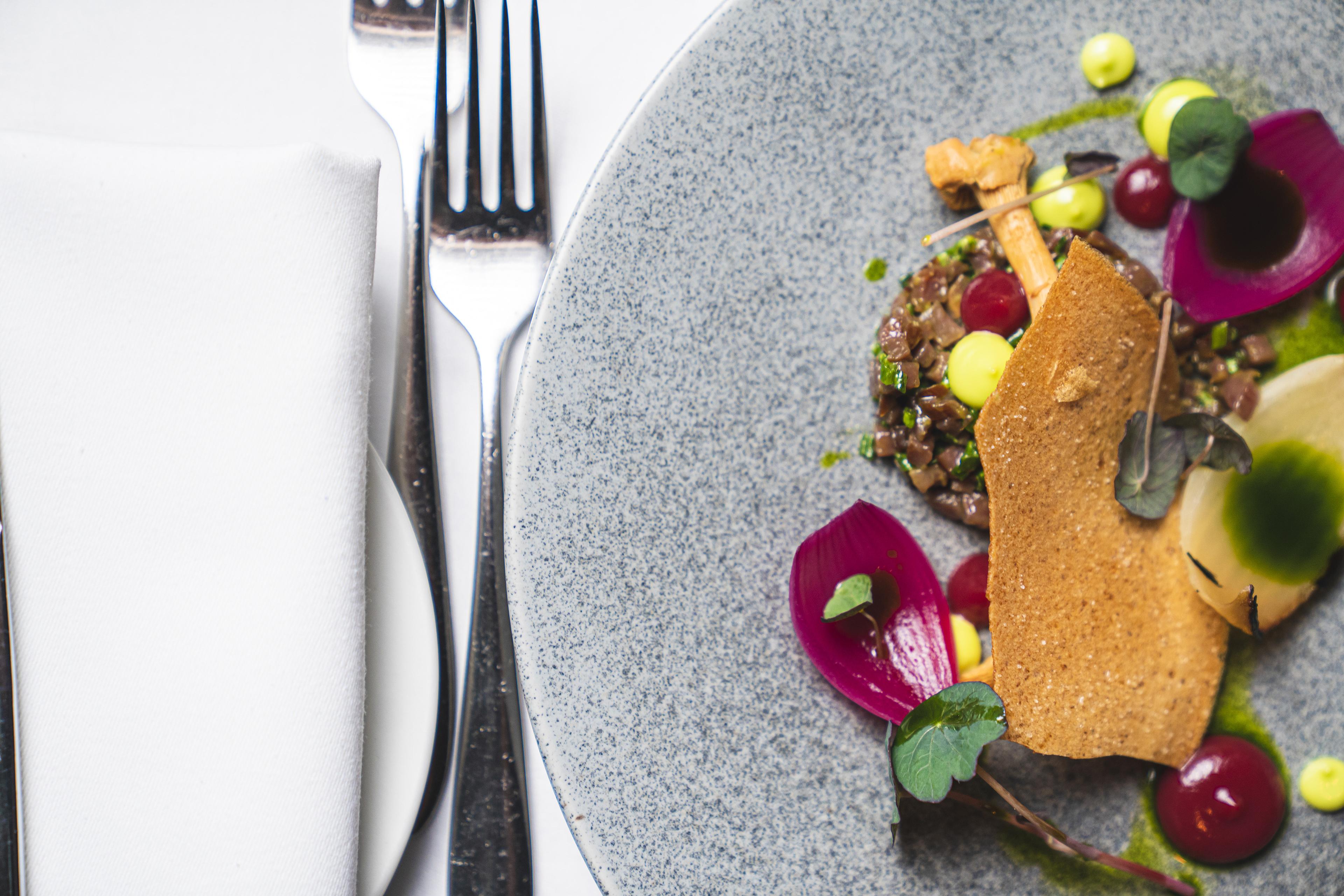 Bild von Teilen eines Tellers mit bunten Speisen, einer Gabel und einer Serviette.