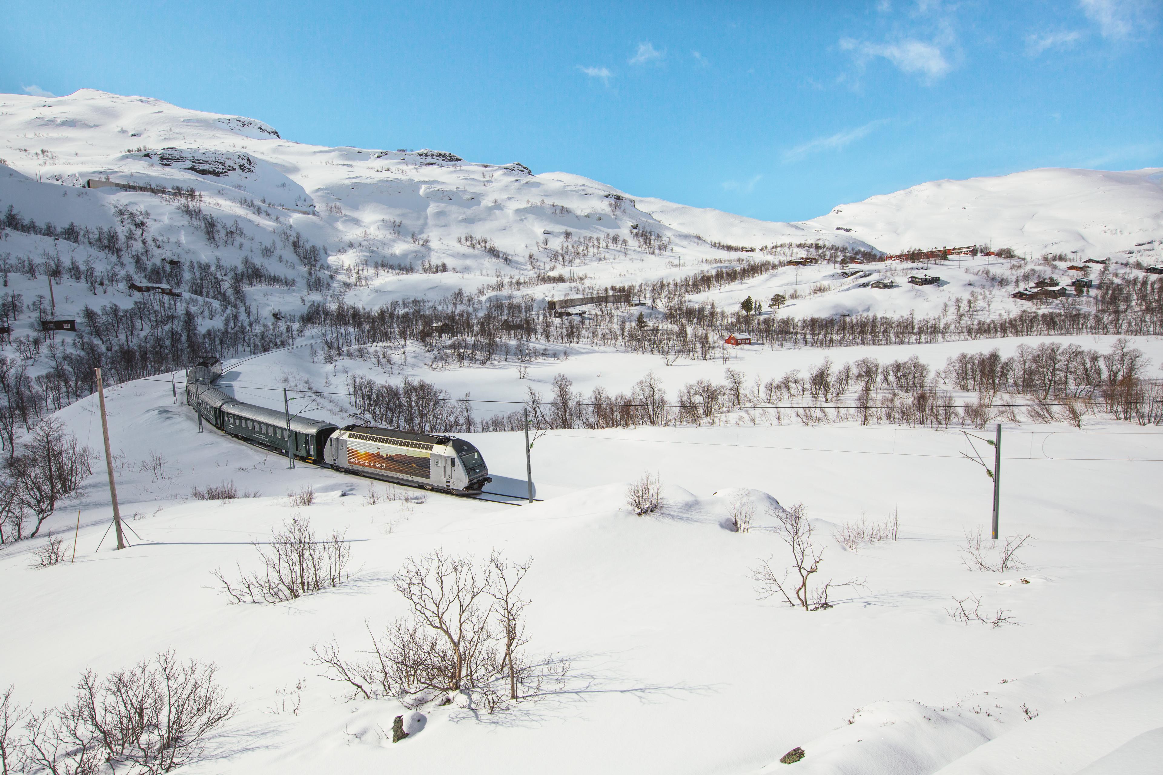 The Flåmsbana curves through a snow-covered valley.