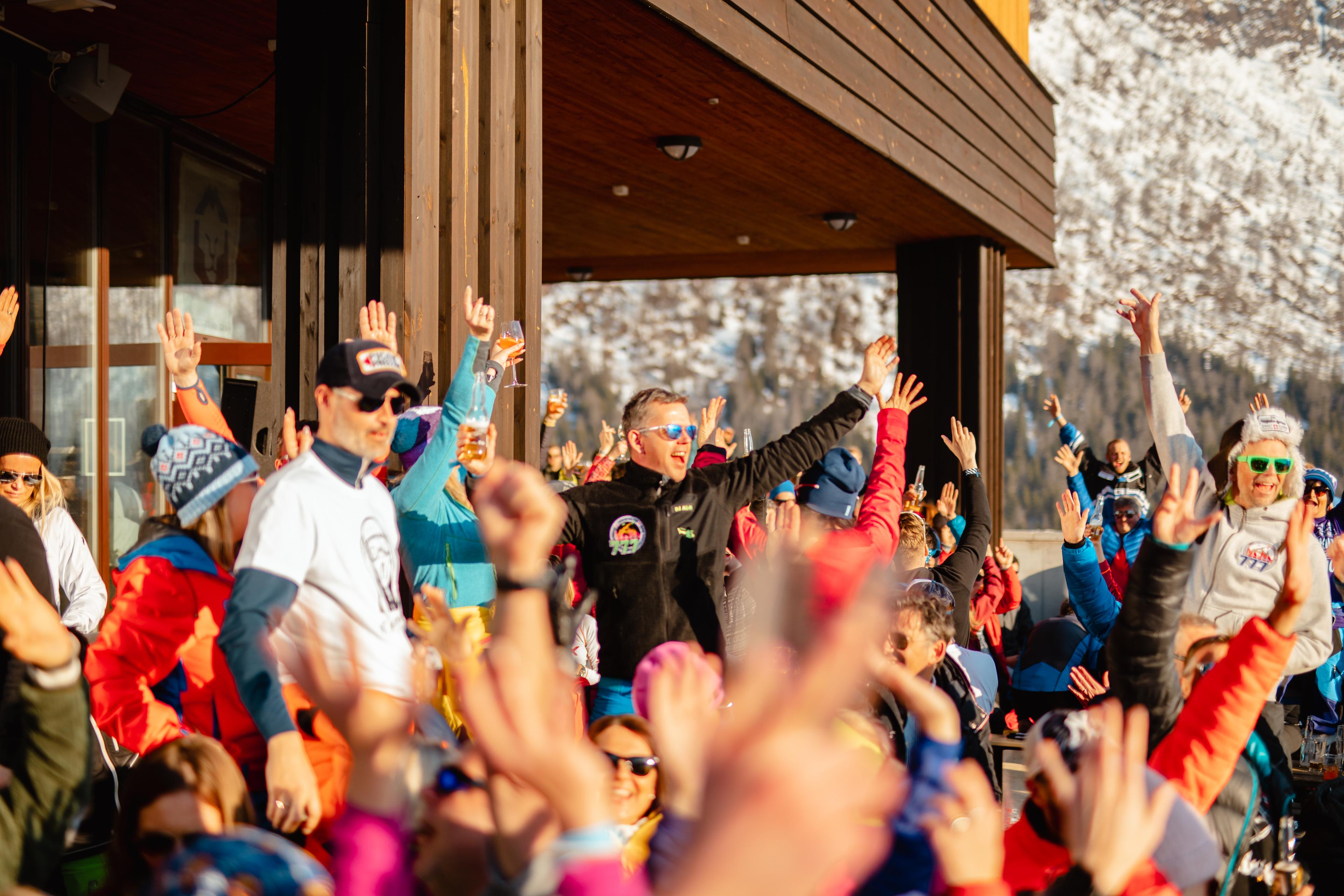 A large group of people are basking in the sun and raising their arms in the air